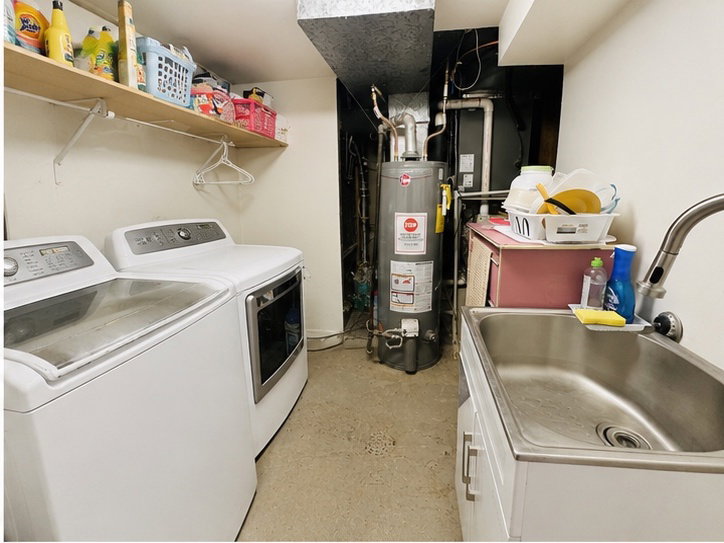 Dedicated utility space featuring a stainless steel utility sink with a gooseneck faucet, a water heater, and exposed overhead ductwork. Washer and dryer not included on sale.