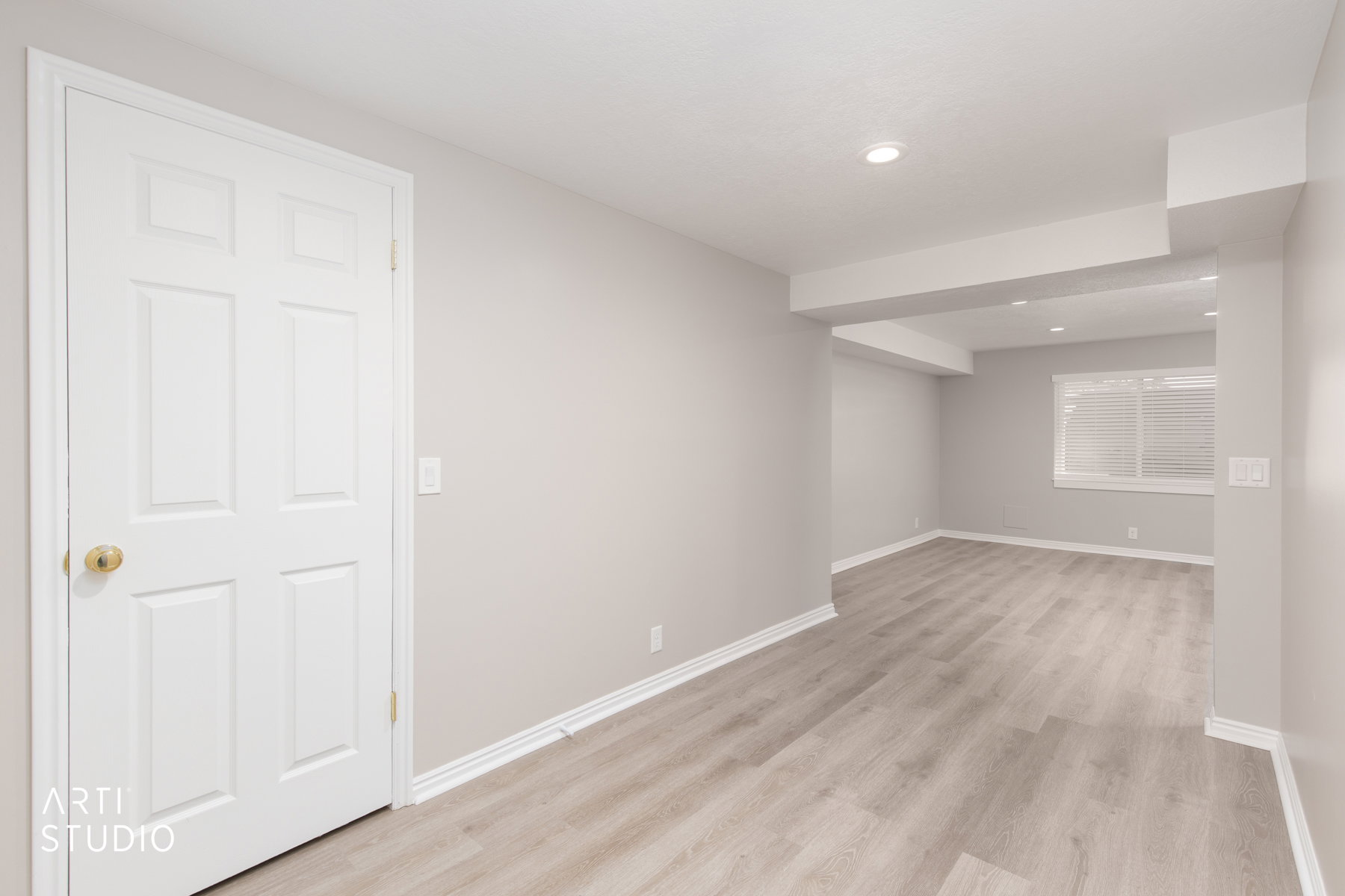 Spacious room featuring wood-finish flooring, recessed lighting, a window with horizontal blinds, and a white paneled door
