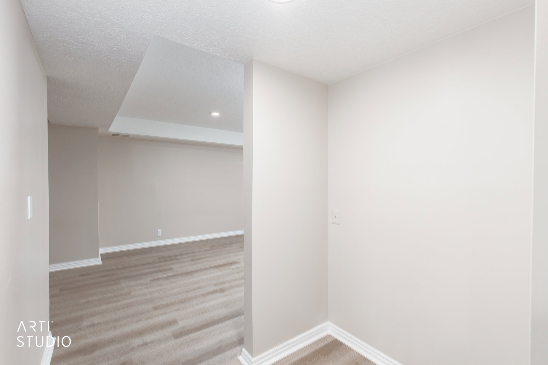 Spacious interior room featuring wood-finish flooring, recessed lighting, and crisp white baseboards