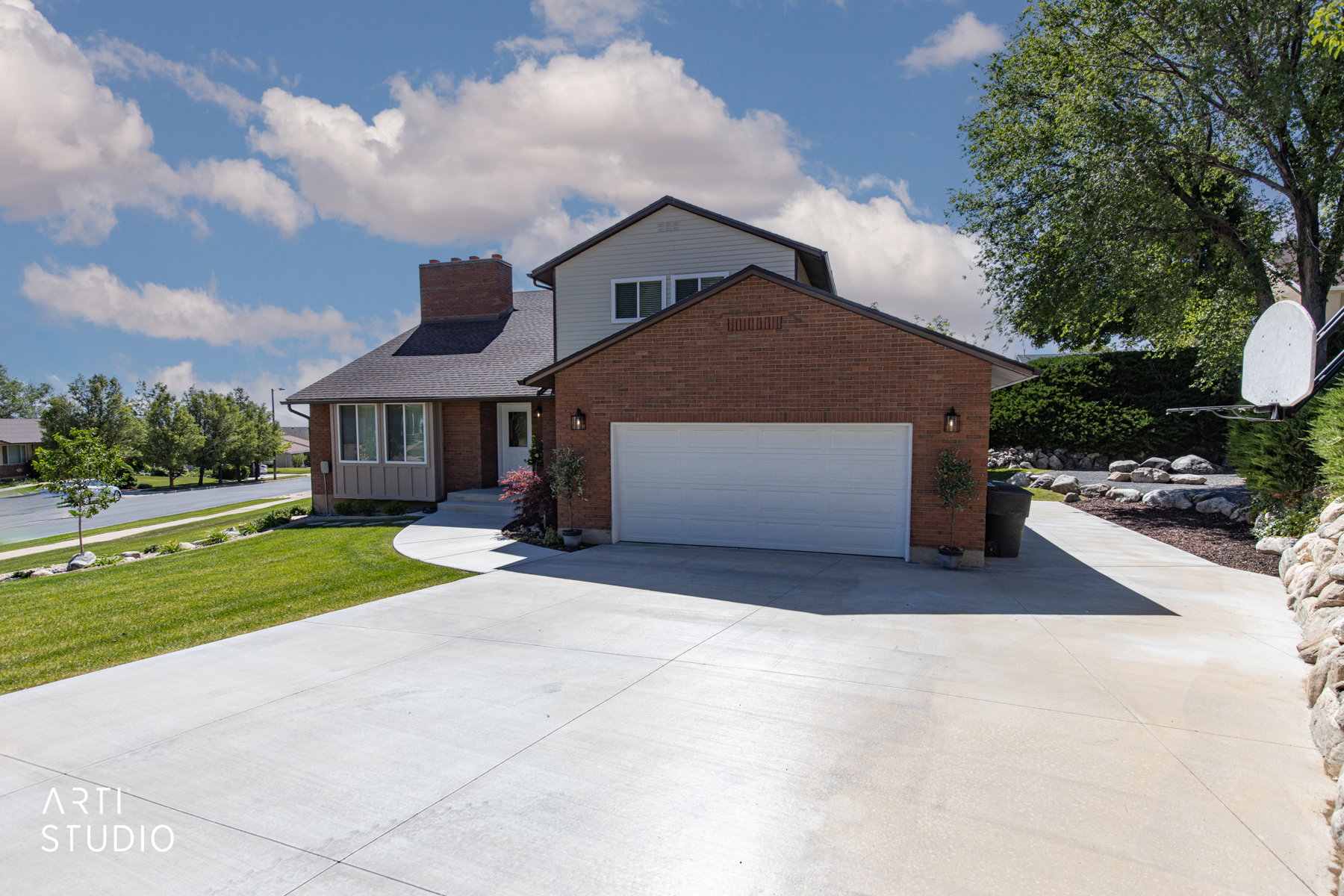 Brick and siding exterior with an attached garage, paved driveway, and manicured front lawn