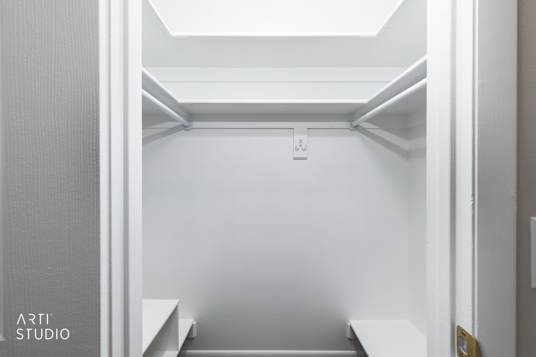 Walk-in closet featuring white painted walls, upper shelving, hanging rods, and lower built-in shelving