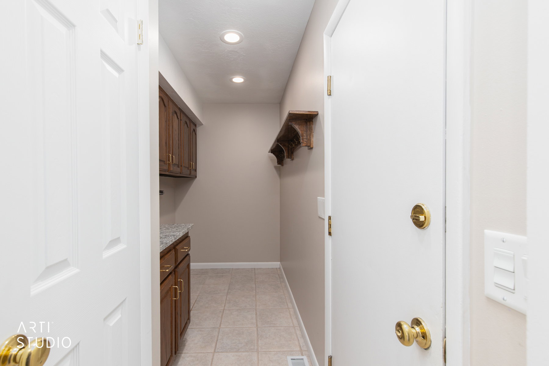 Utility area featuring wood cabinetry with brass hardware, speckled countertop, and recessed lighting