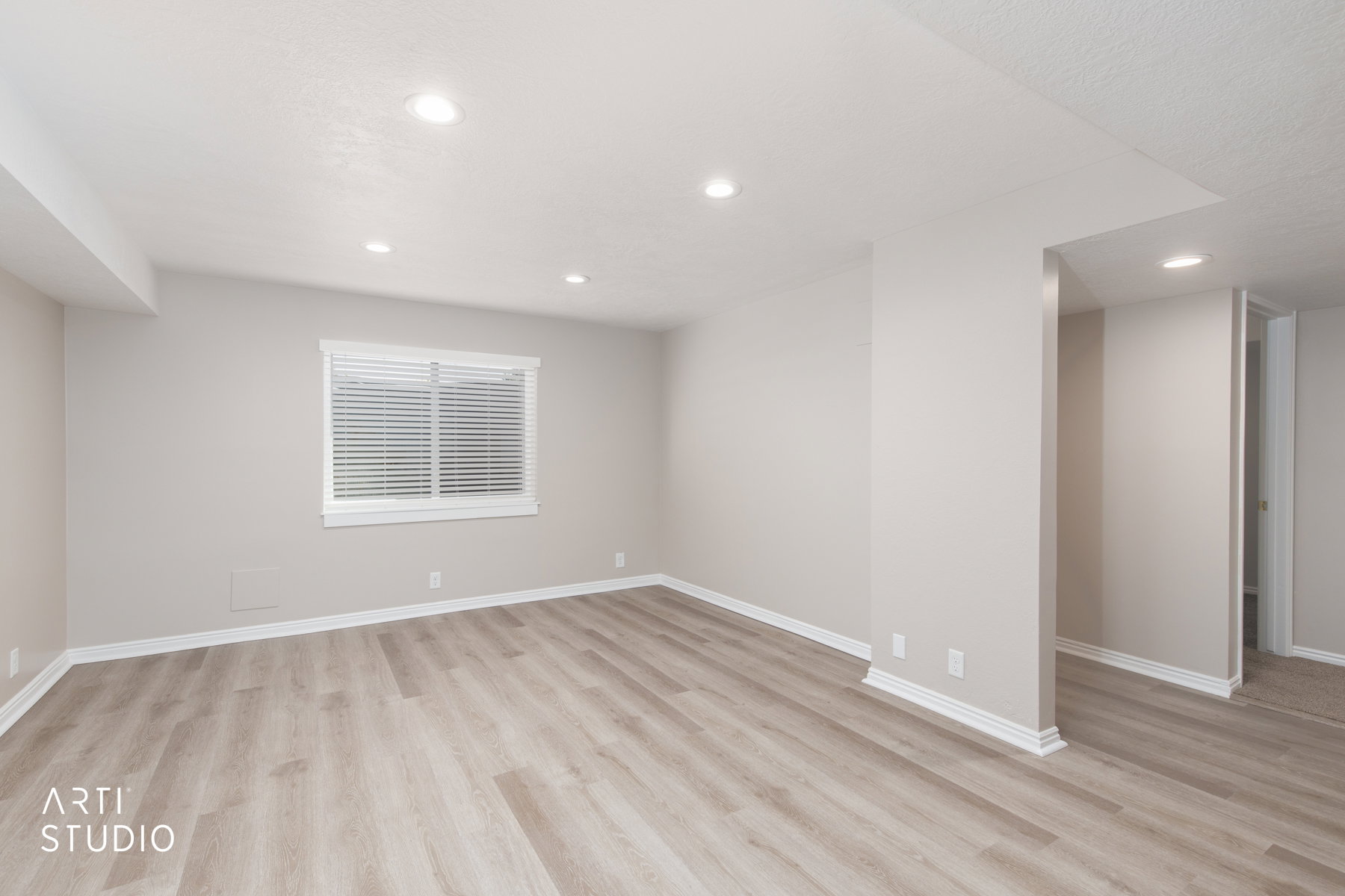 Spacious room featuring wood-finish flooring, recessed lighting, a window with blinds, and neutral wall tones