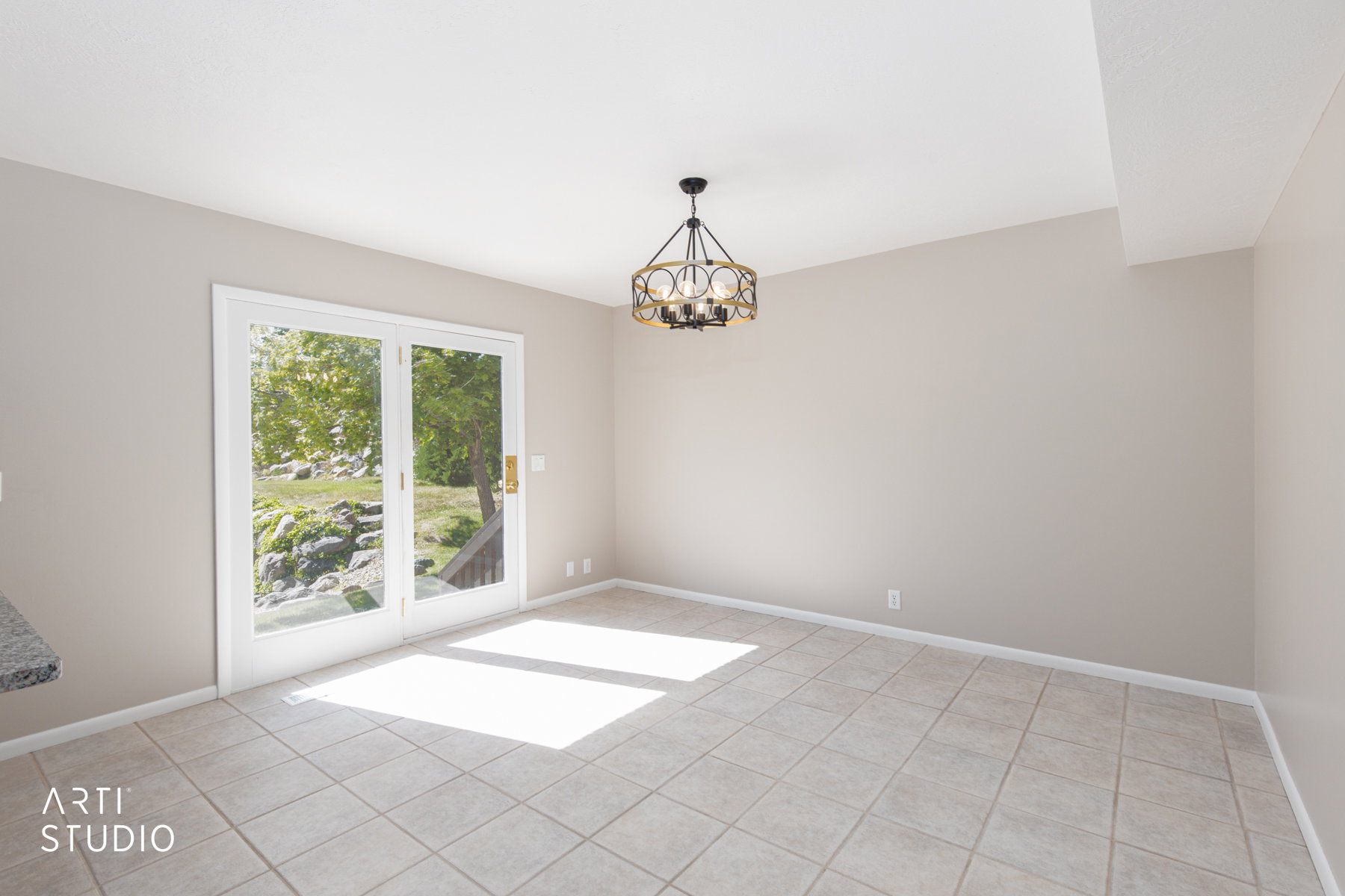 Spacious room featuring neutral-toned walls, tile flooring, and a contemporary chandelier