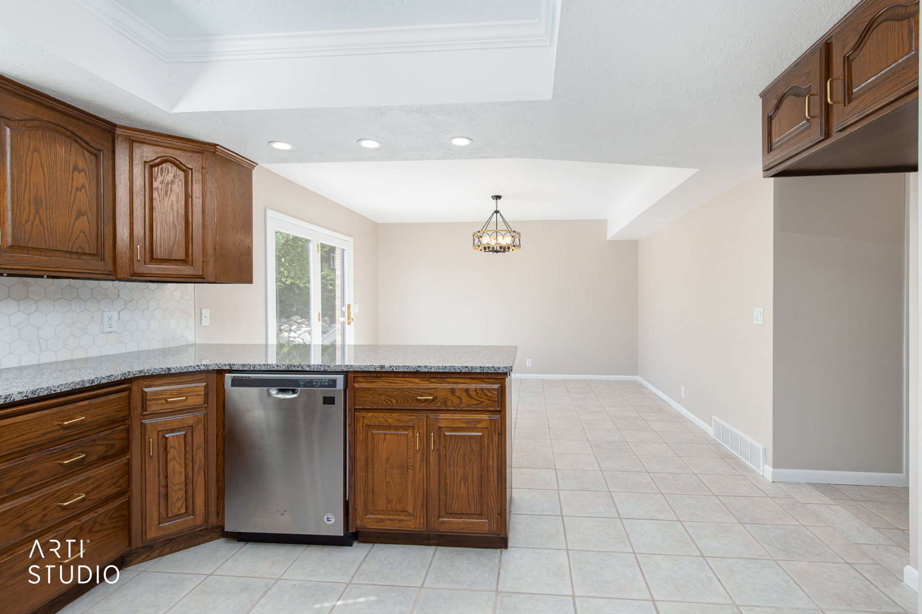 Kitchen featuring wood cabinetry, a stainless steel dishwasher, and a stone-finish countertop