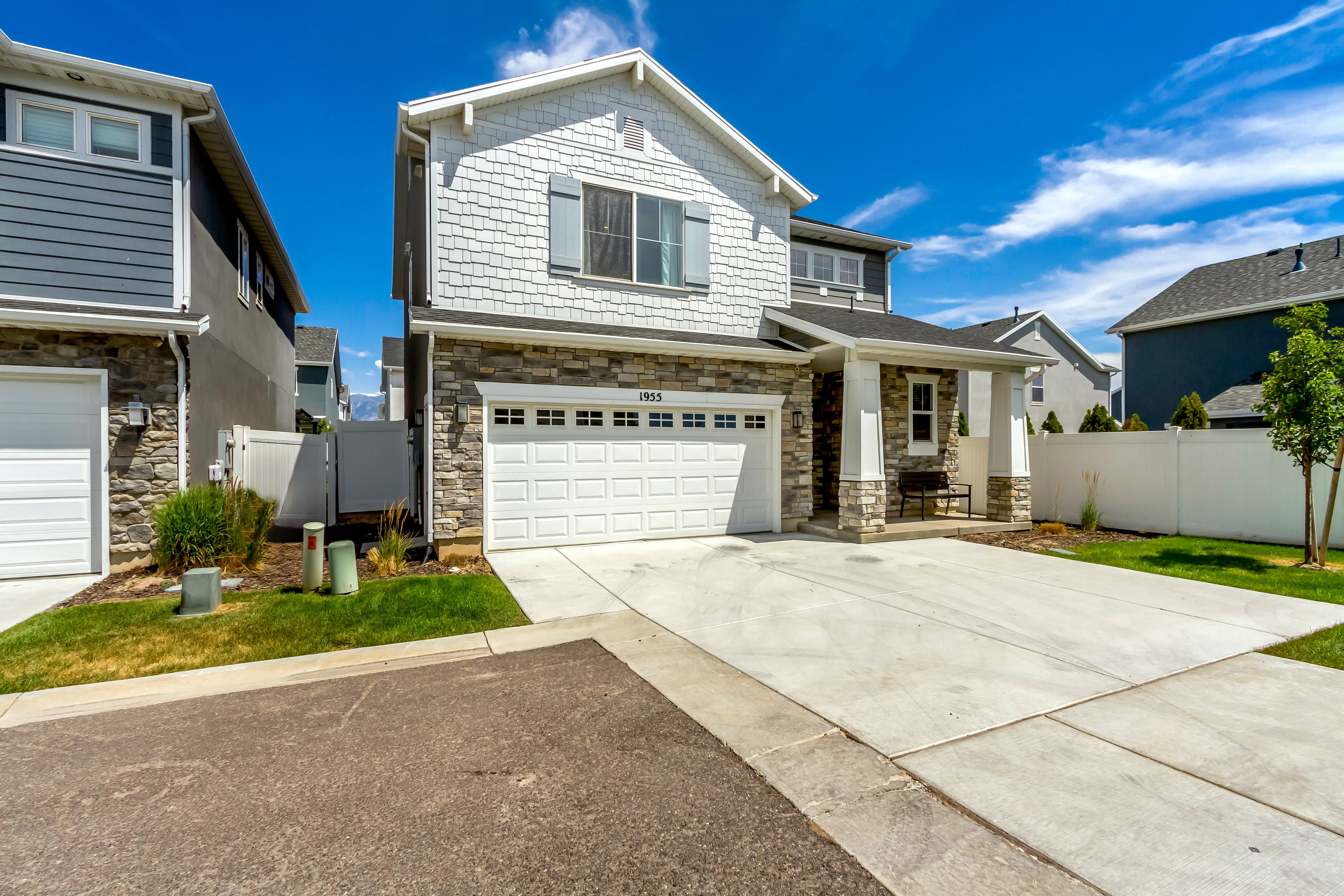 Contemporary residence featuring a stone and shingle facade, an attached garage, and a covered entry
