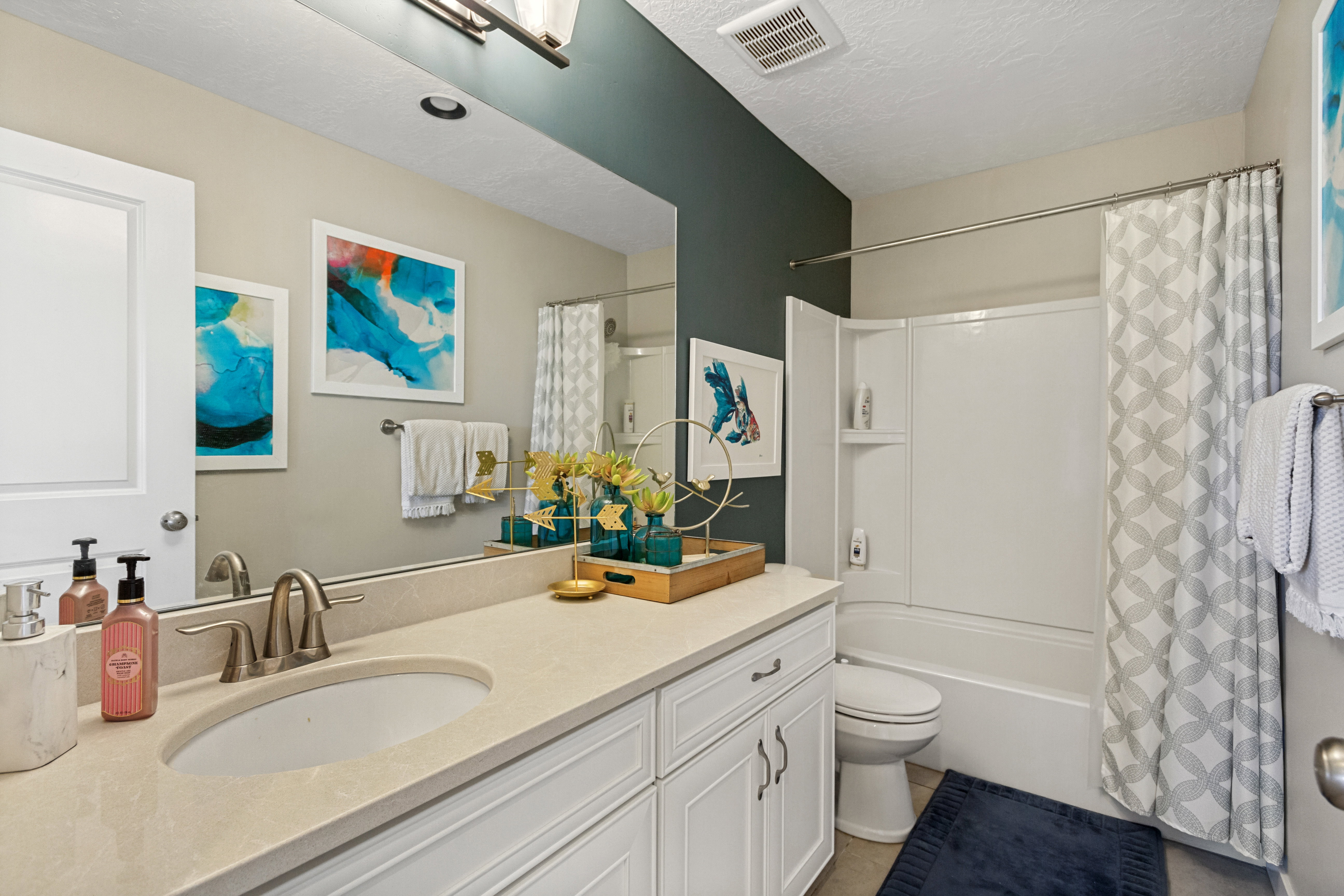 Bathroom vanity with an integrated sink and light-toned countertop, complete with a wide mirror