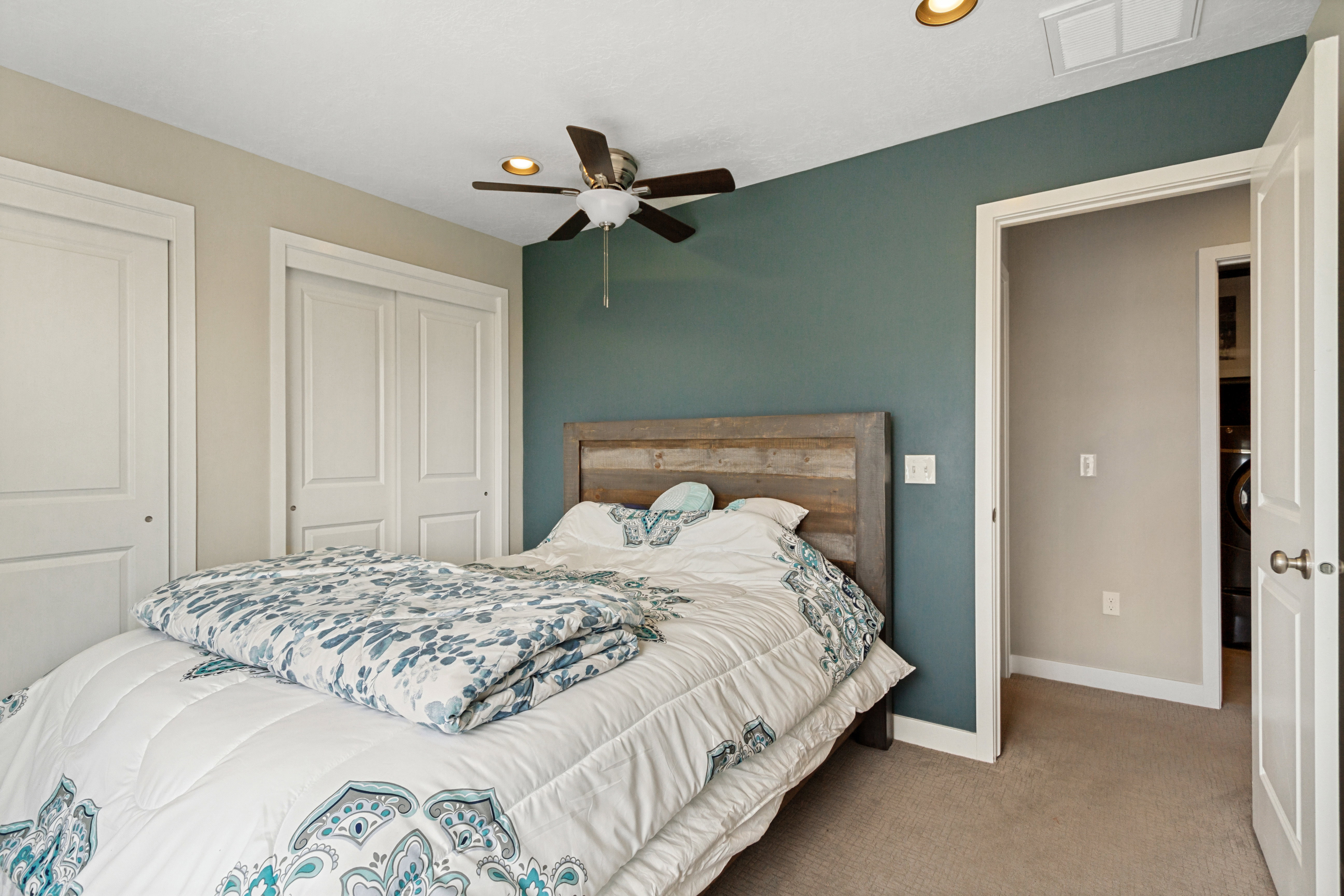 Bedroom featuring a wood-finish headboard, a ceiling fan with integrated lighting, and carpet flooring