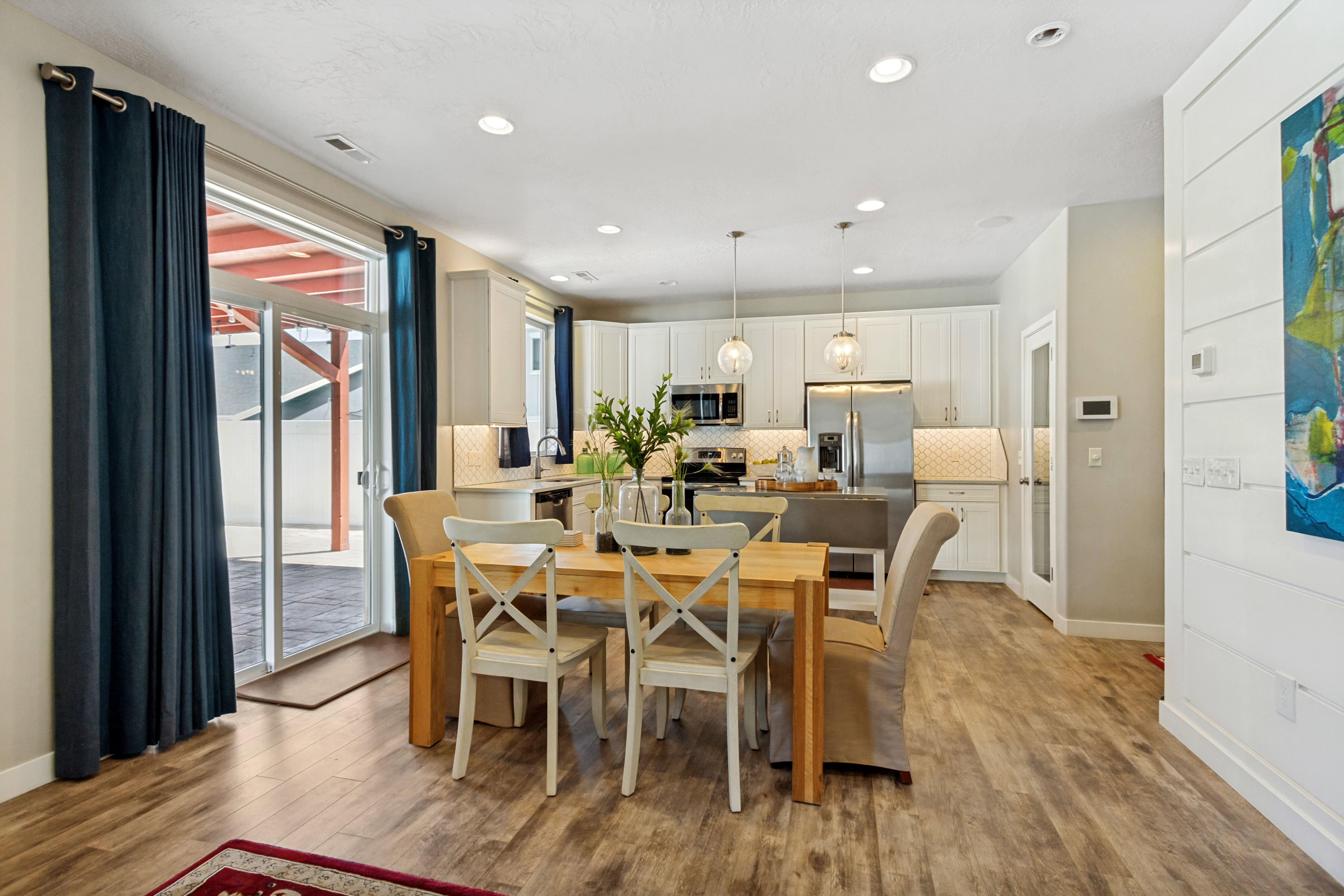 Kitchen and dining area featuring wood-finish flooring, recessed lighting, and white cabinetry