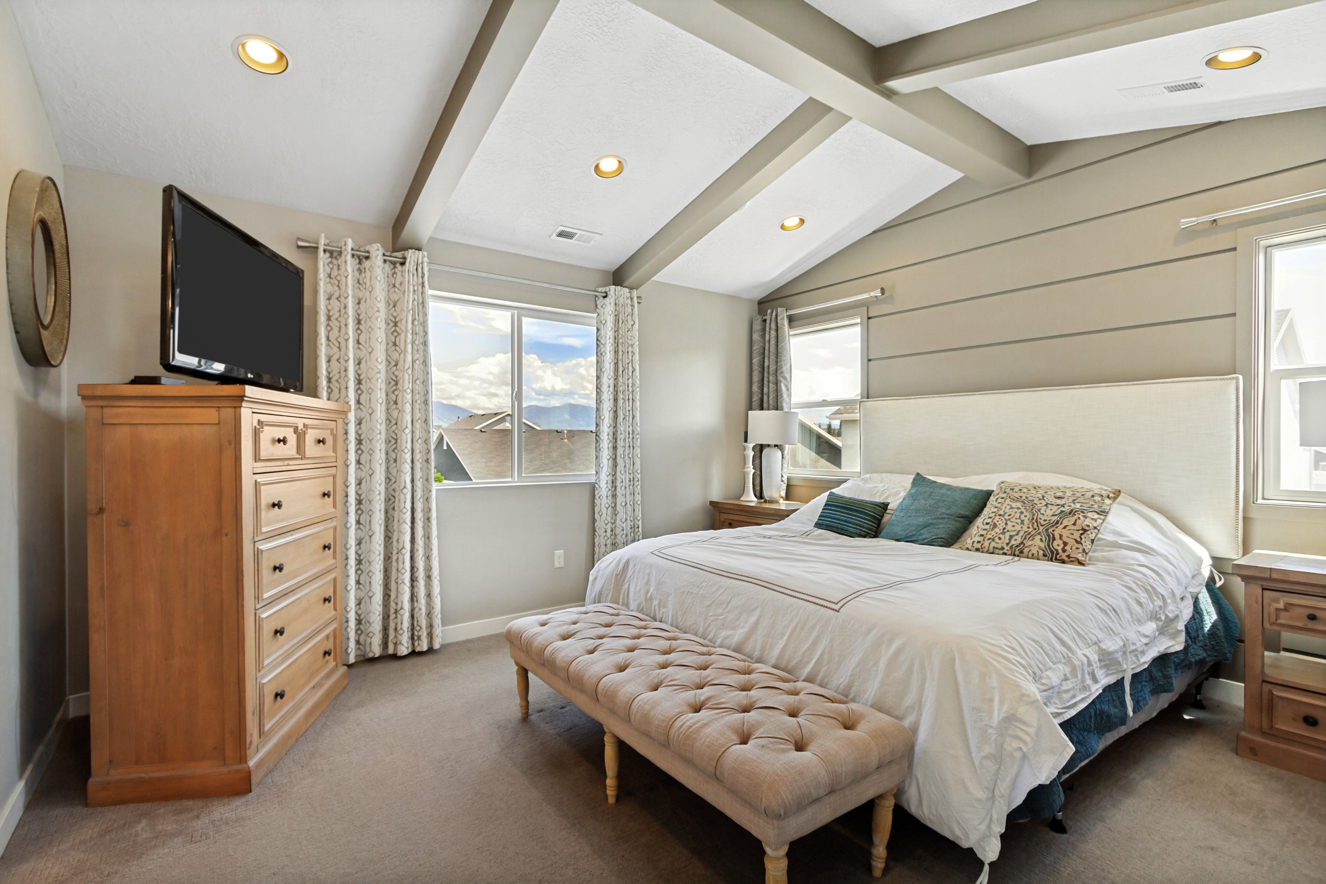 Vaulted ceiling with exposed beams, recessed lighting, and shiplap accent wall