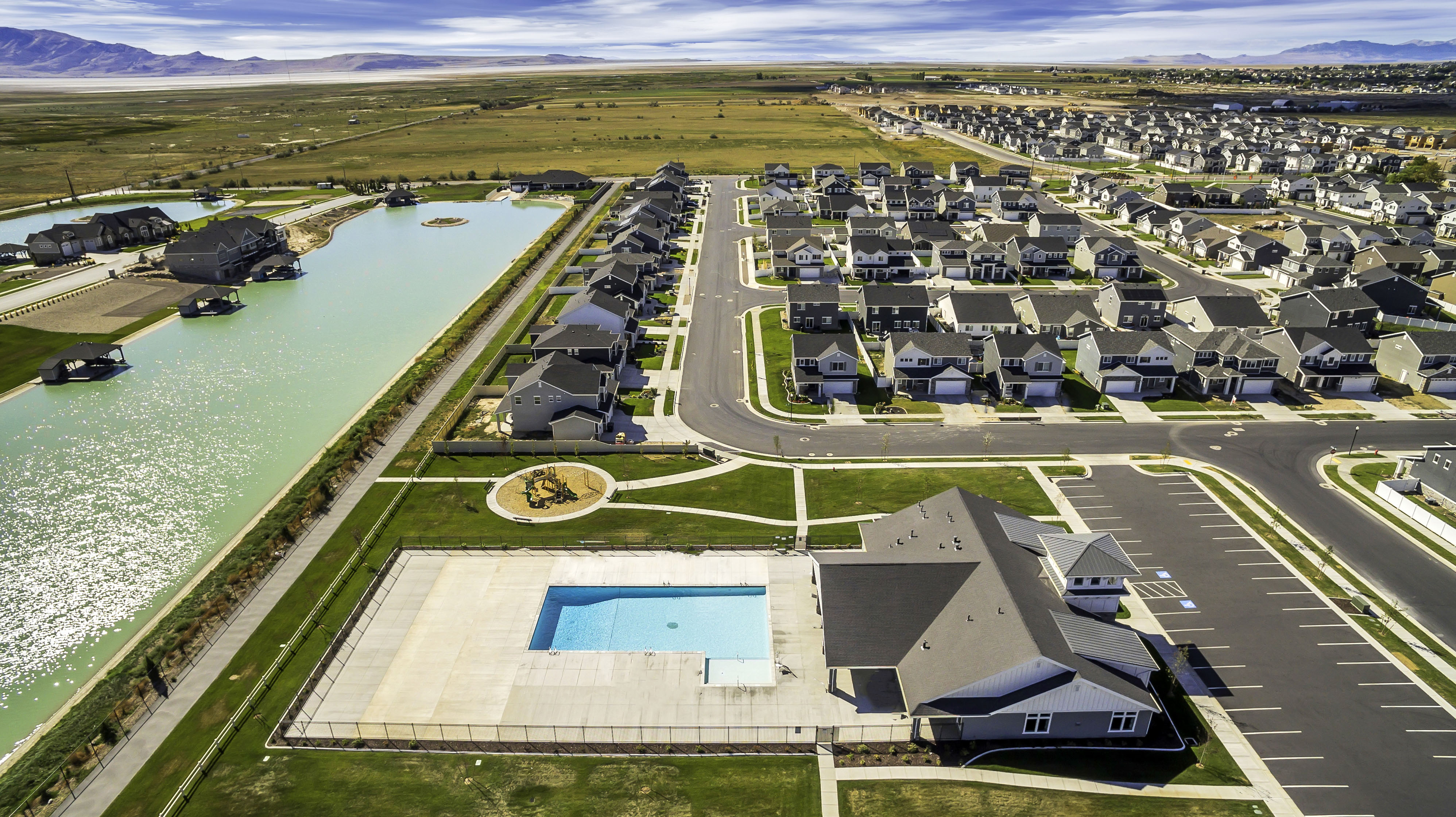 Community setting featuring a large aquatic amenity, structured street layout, and a community building with an adjacent swimming pool and parking area