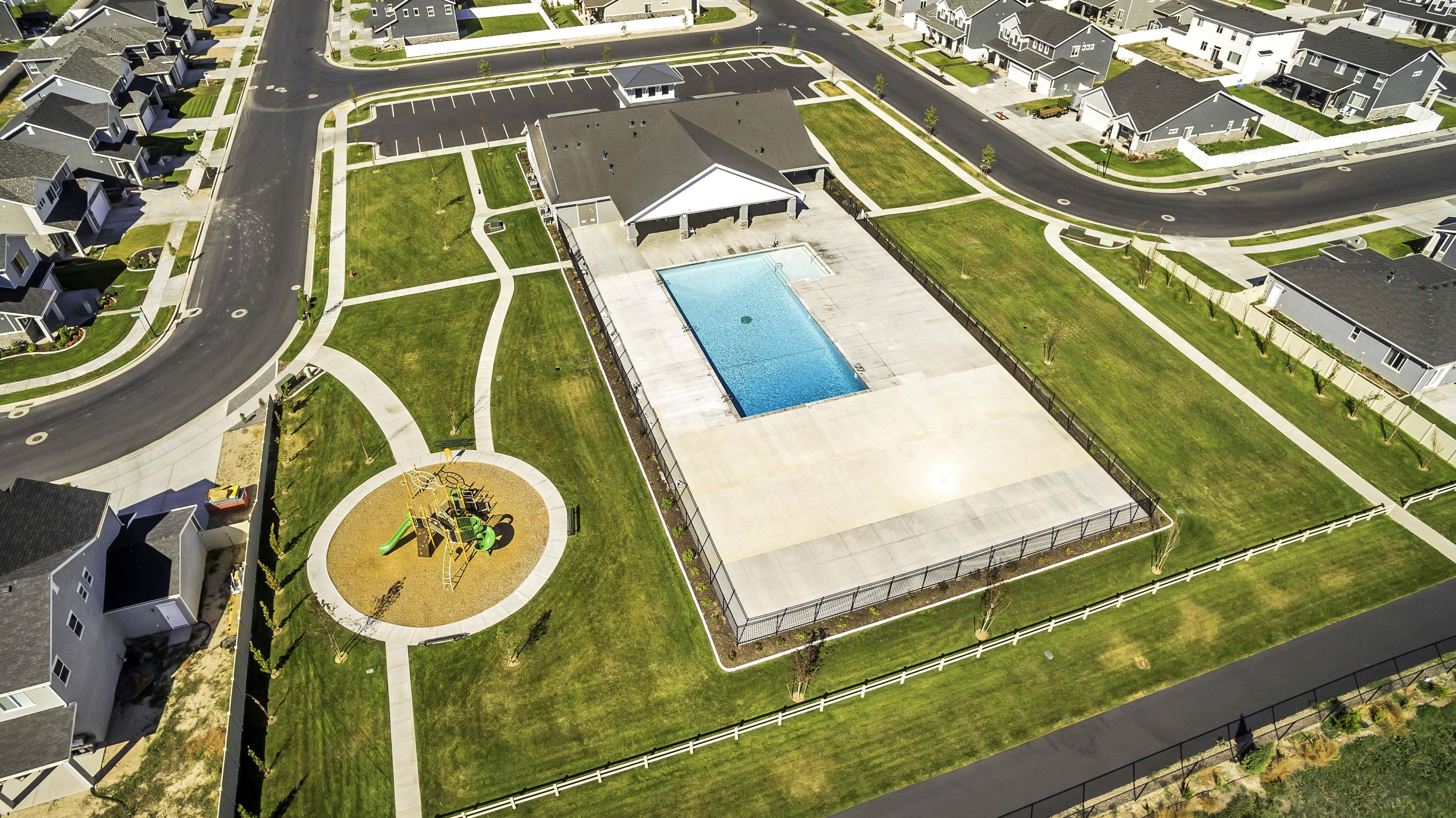 Community recreation area featuring a fenced swimming pool, adjacent club house, and a children's play structure