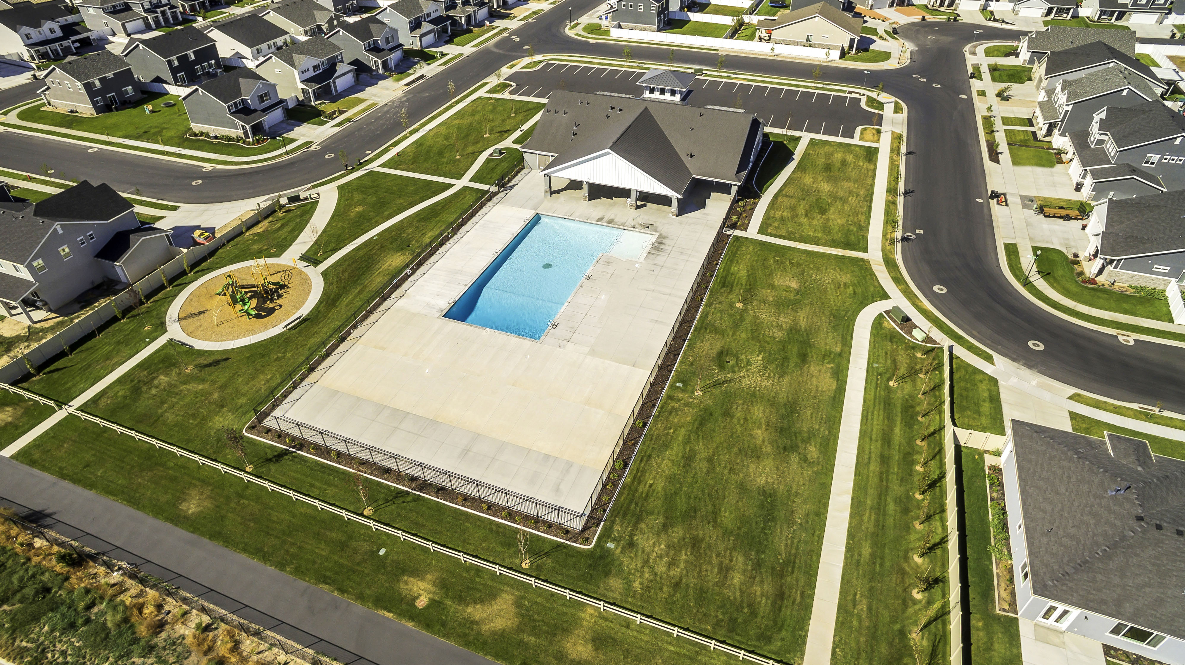 Community recreation area featuring a swimming pool, clubhouse with covered patio, and adjacent playground