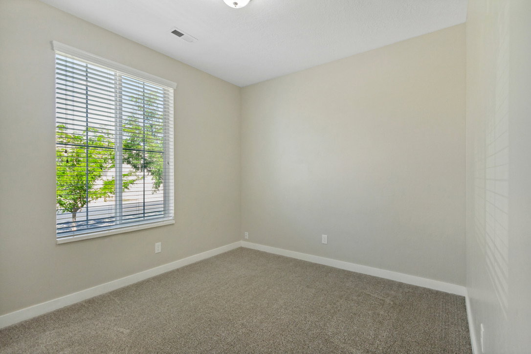 Neutral-toned room with carpet flooring and a window featuring horizontal blinds