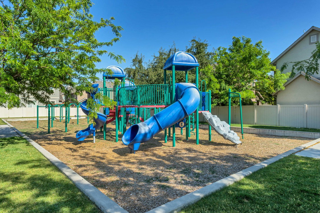 Community playground featuring blue and green play structures, slides, and climbing elements