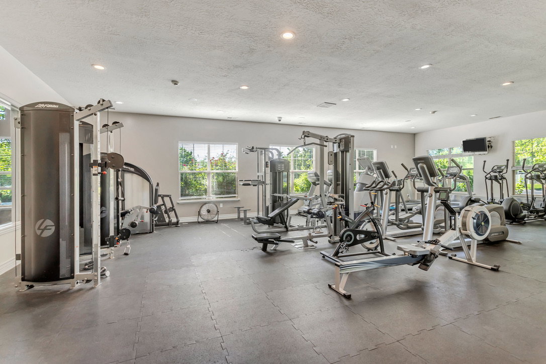 Clubhouse has a spacious fitness area featuring a variety of exercise equipment, recessed lighting, multiple windows, and durable interlocking floor mats