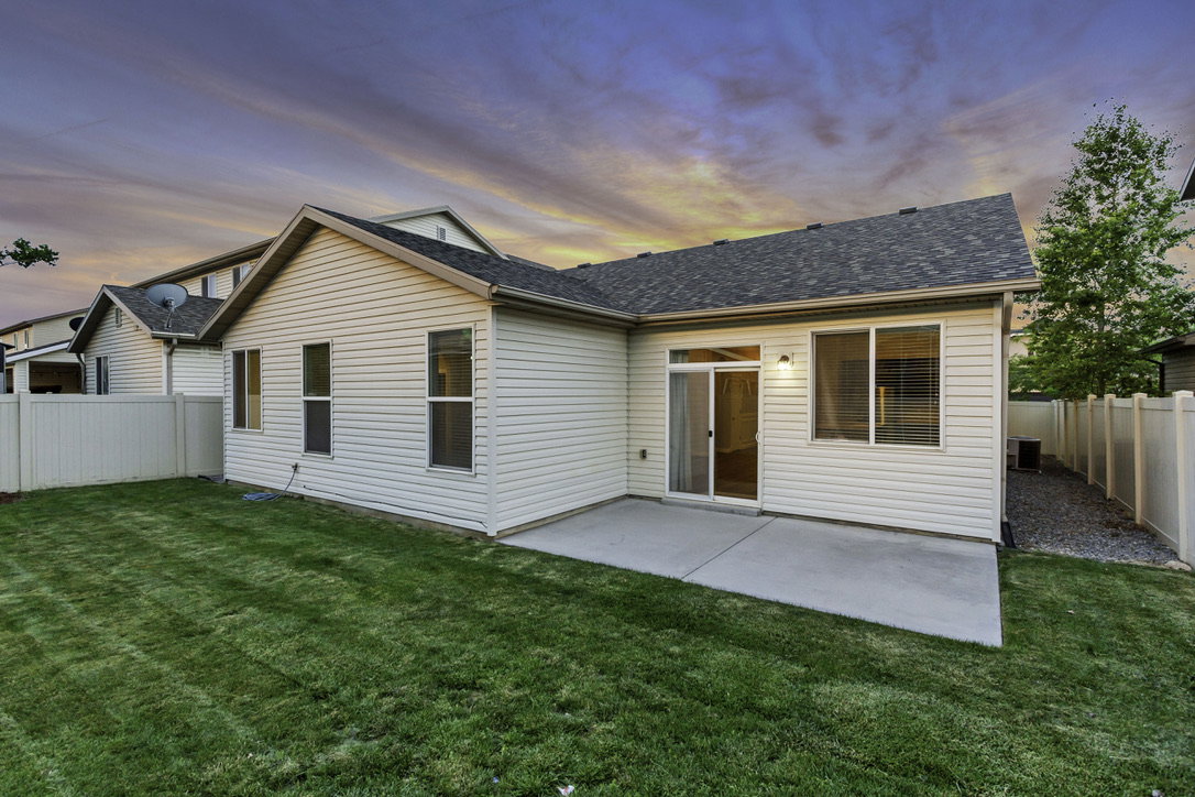 Expansive backyard featuring a manicured lawn, concrete patio, and privacy fencing