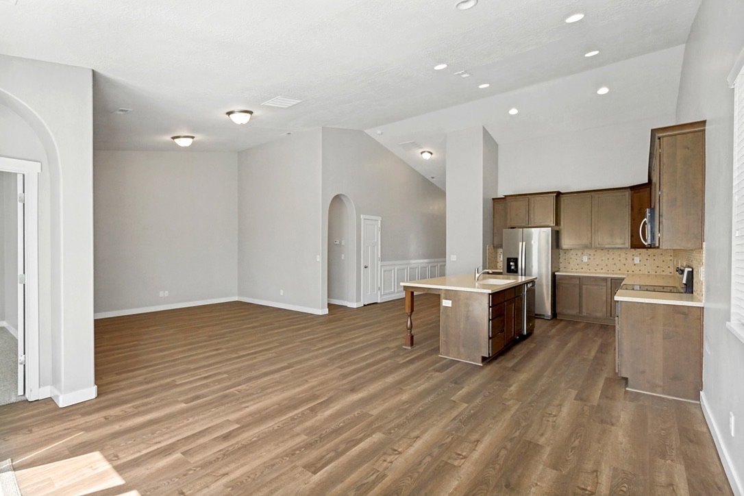 Open-concept living space featuring wood-finish flooring, recessed lighting, and vaulted ceilings