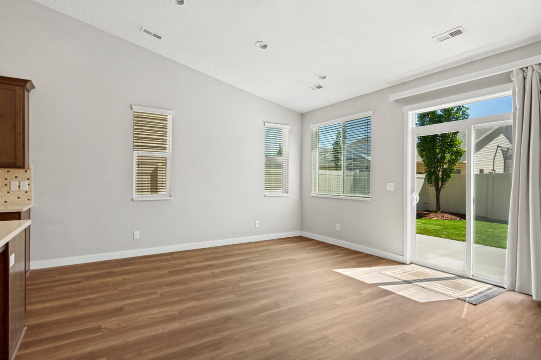 Spacious room featuring wood-finish flooring, a vaulted ceiling with recessed lighting, and multiple windows with blinds