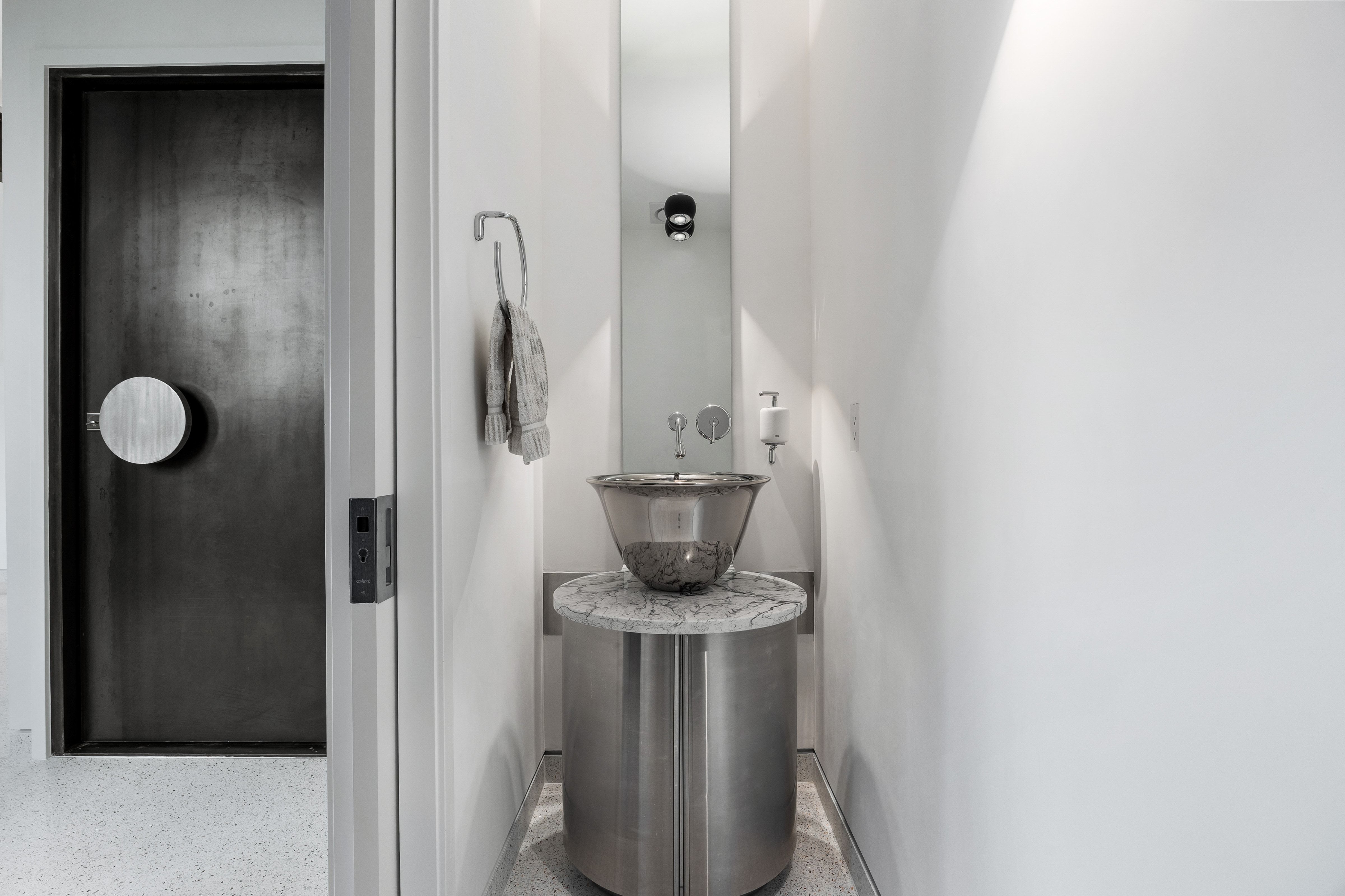 Modern powder room featuring a glass vessel sink set on a round stone countertop