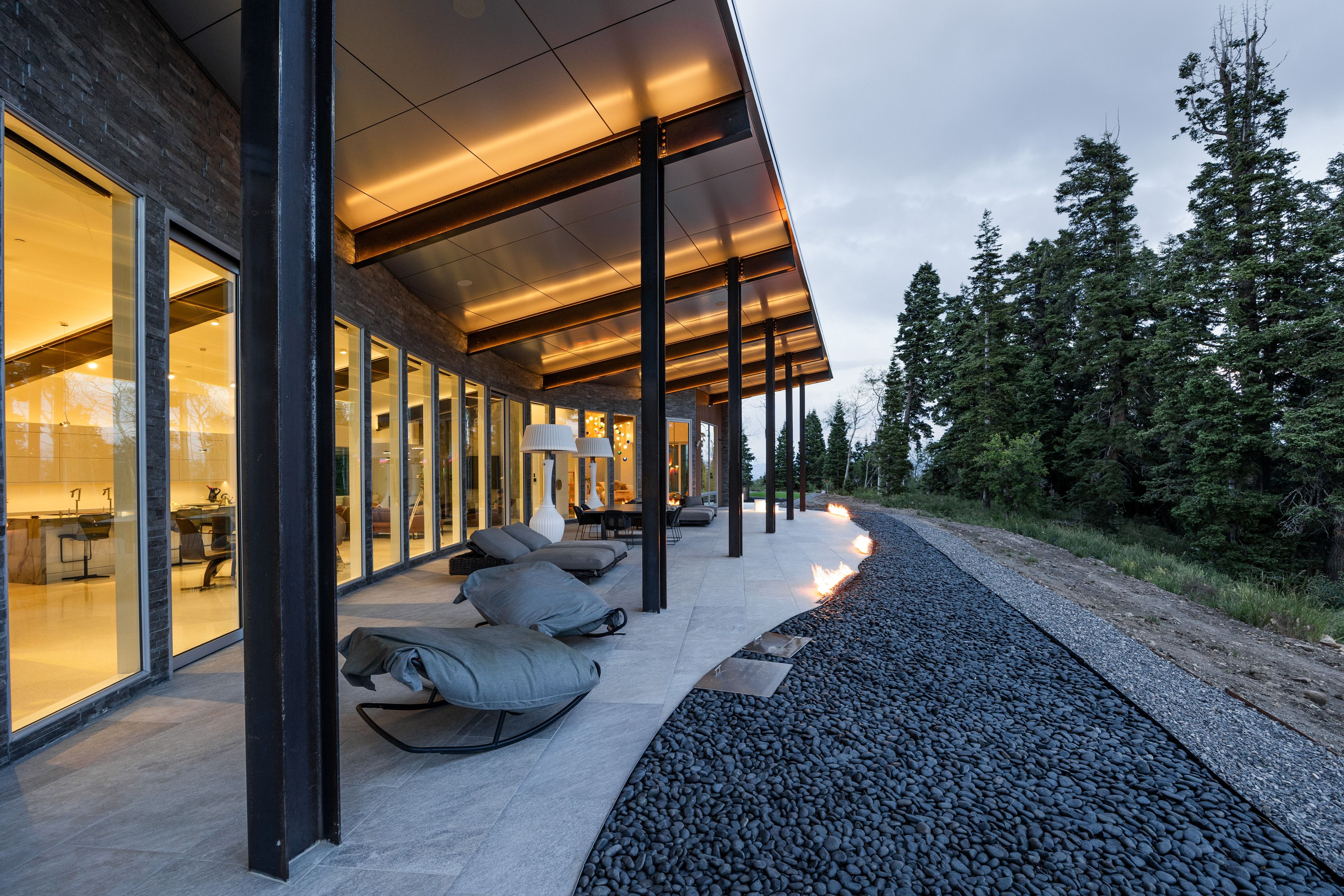 Expansive covered patio featuring sleek tile flooring, black structural beams, and integrated ceiling lighting