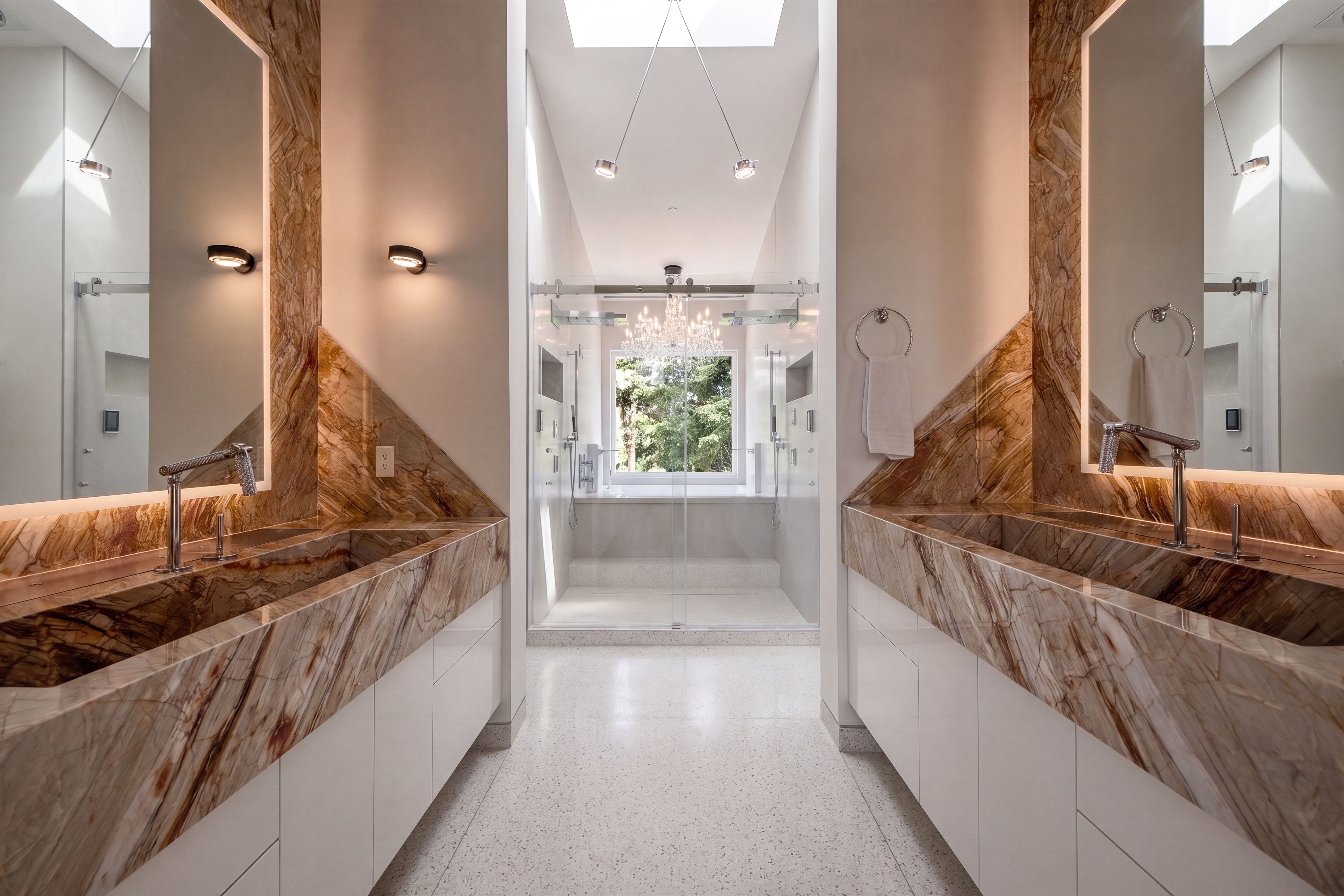 Dual custom stone vanities with integrated sinks and wall-mounted faucets