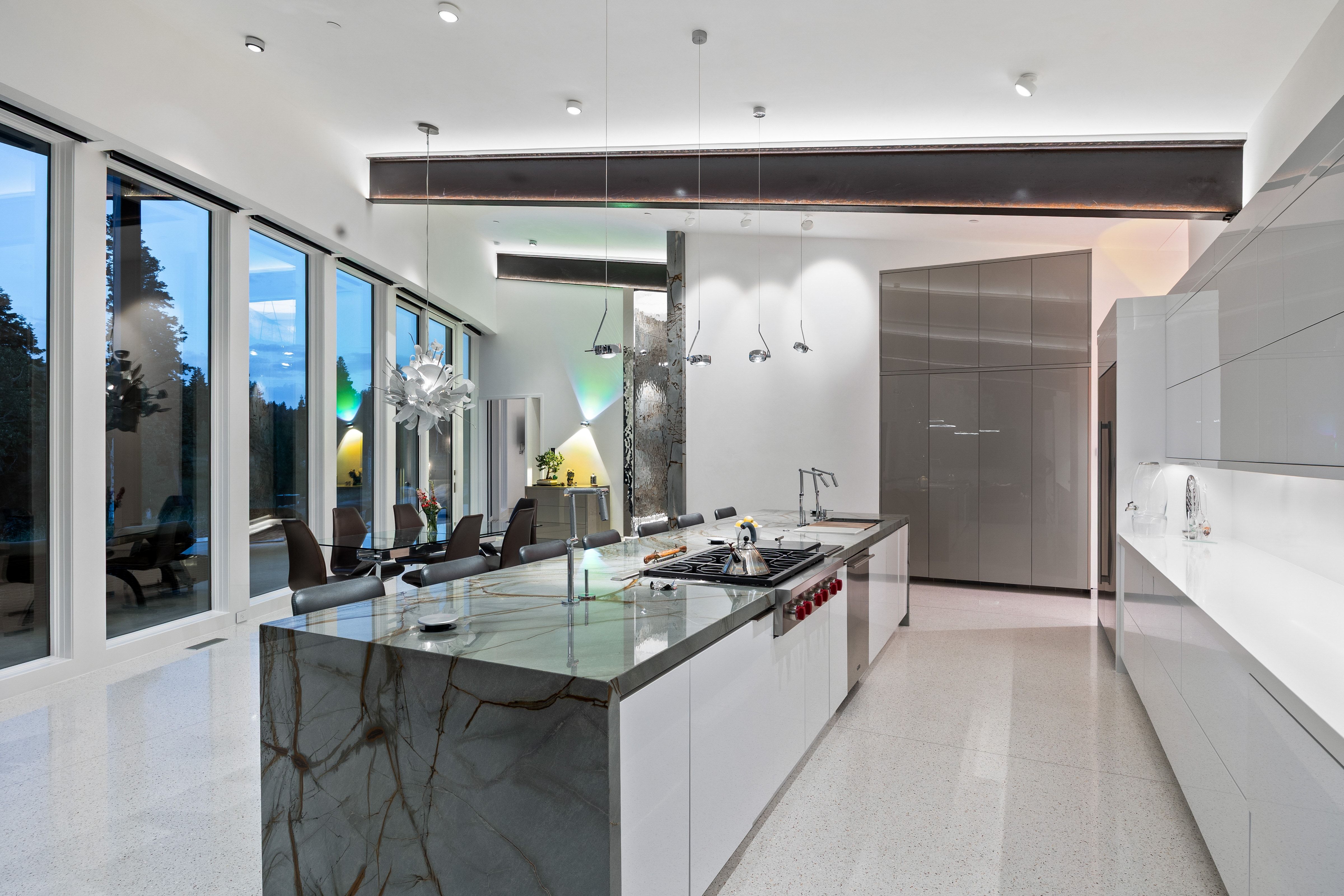 Modern kitchen featuring an expansive island with a waterfall countertop, integrated cooktop, and undermount sink