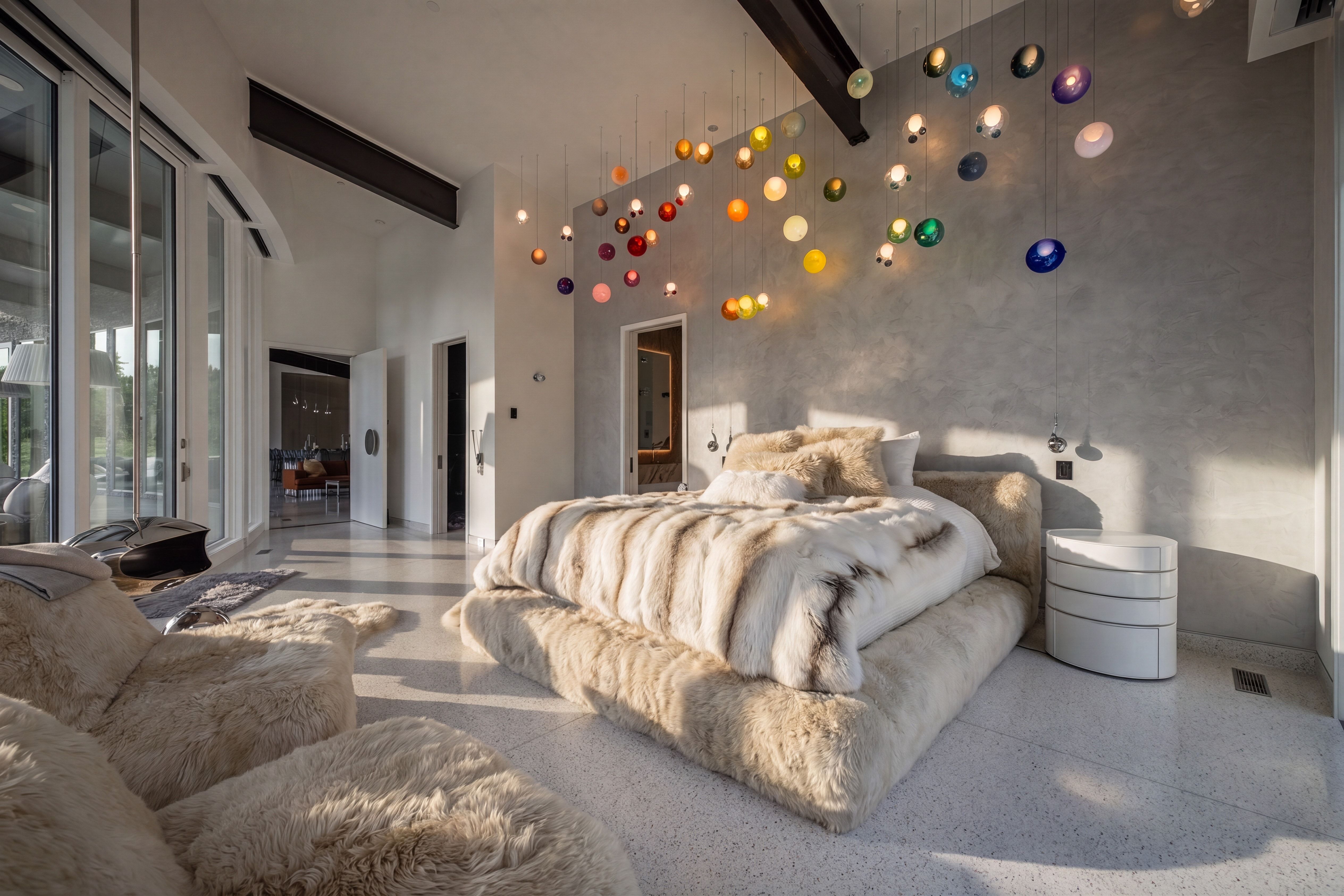 High ceilings featuring exposed beams, a wall of glass sliding doors, textured gray wall finish, and terrazzo flooring