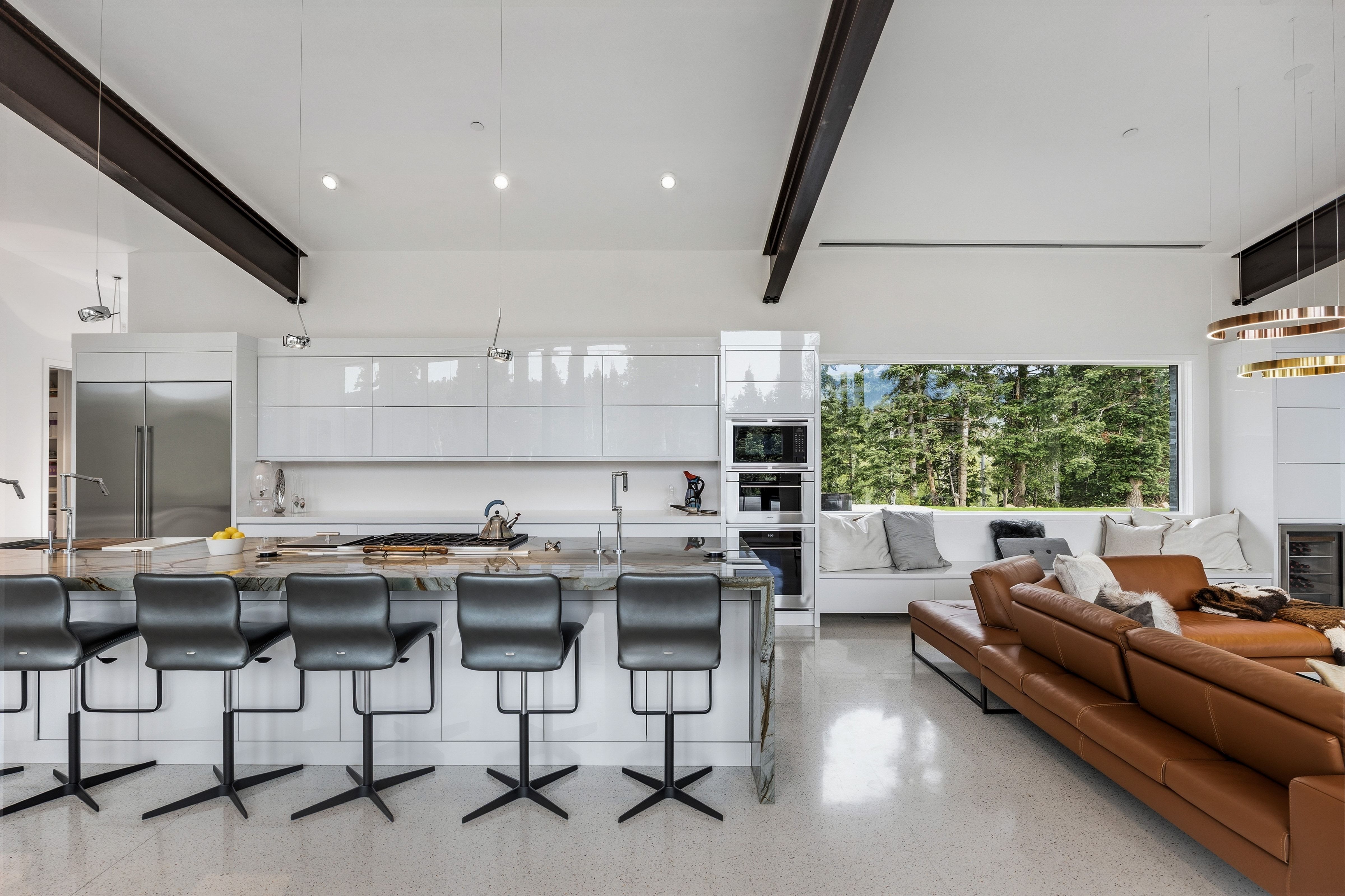 Open concept living space featuring a modern kitchen island with integrated seating, high-gloss white cabinetry, and stainless steel appliances