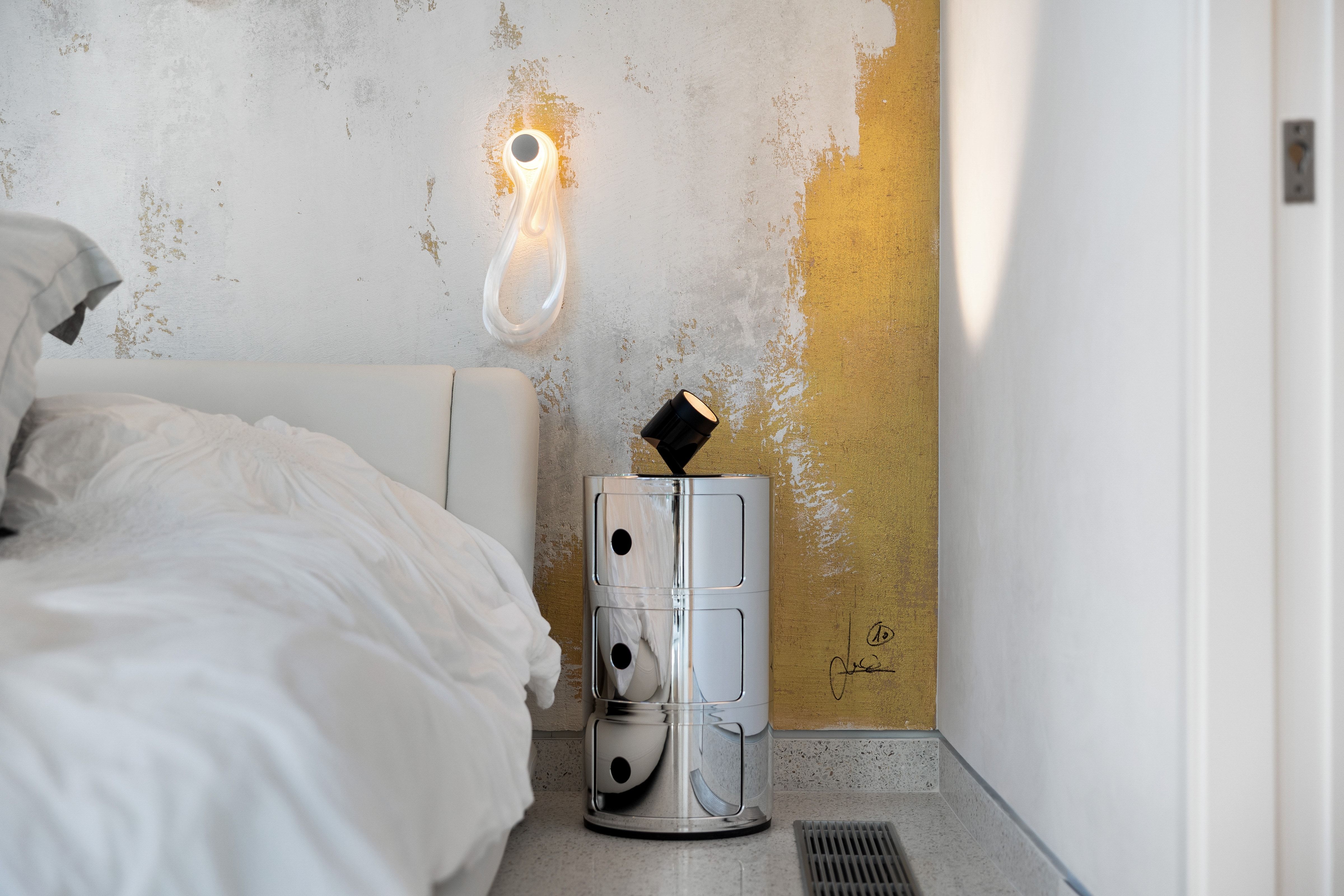 Accent wall with distressed metallic finish and contemporary sconce lighting