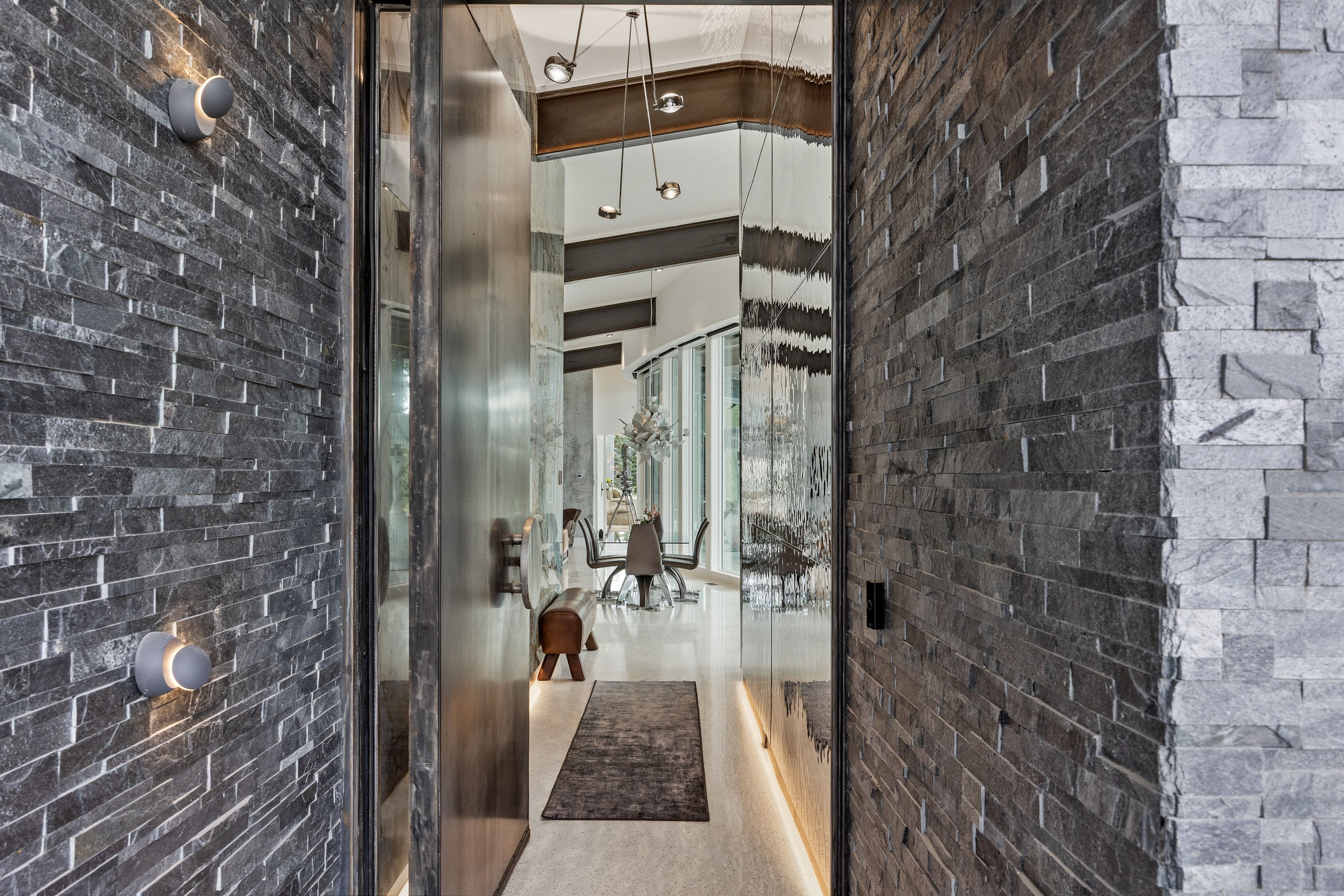 Entryway featuring stacked stone walls, a large pivot door, and recessed wall lighting