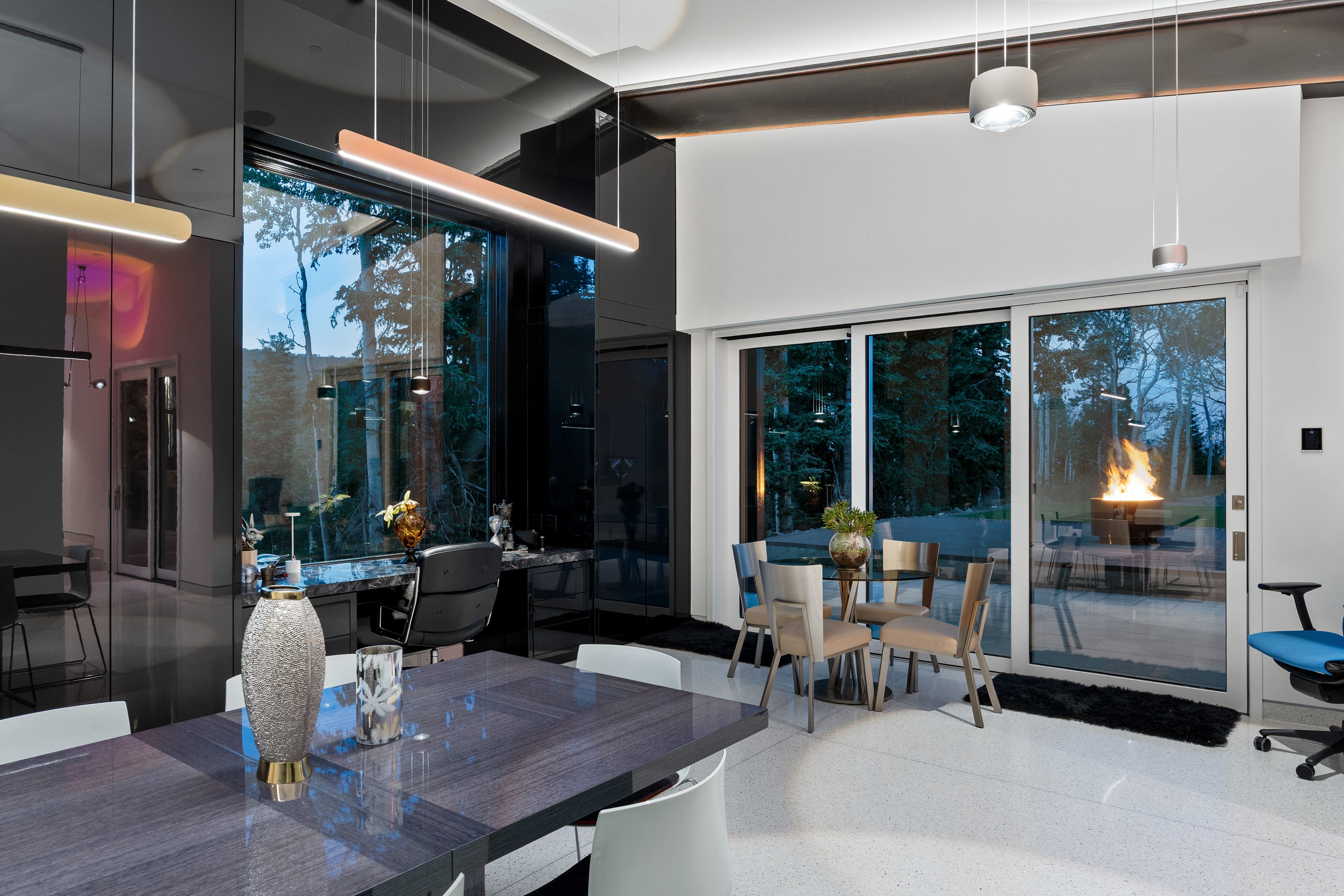 Spacious interior featuring a large format tile floor, expansive sliding glass doors, built-in desk with a dark stone-finish surface, and multiple pendant light fixtures
