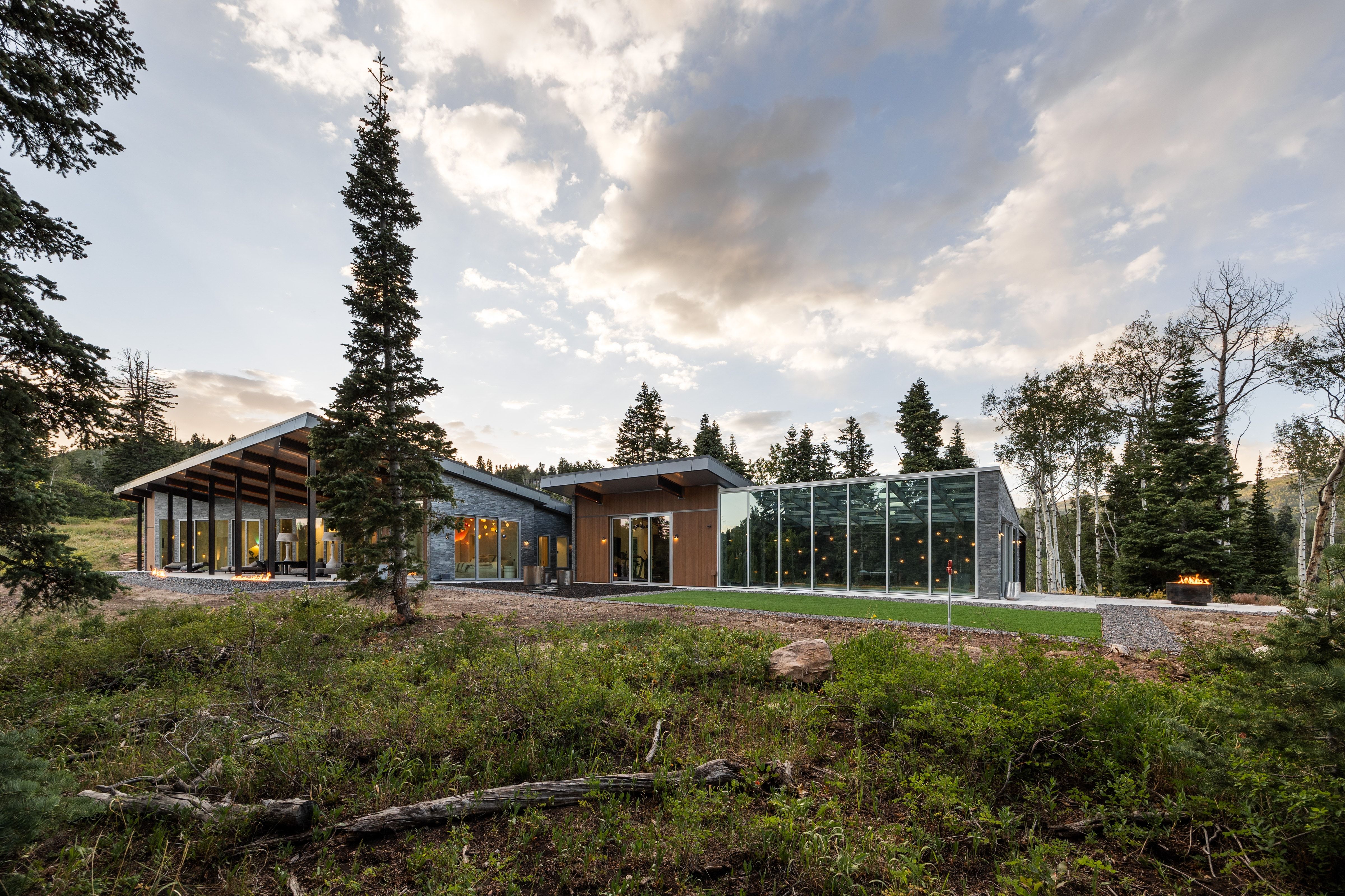 Contemporary architecture featuring extensive glass walls, a sloping roofline, and natural wood accents