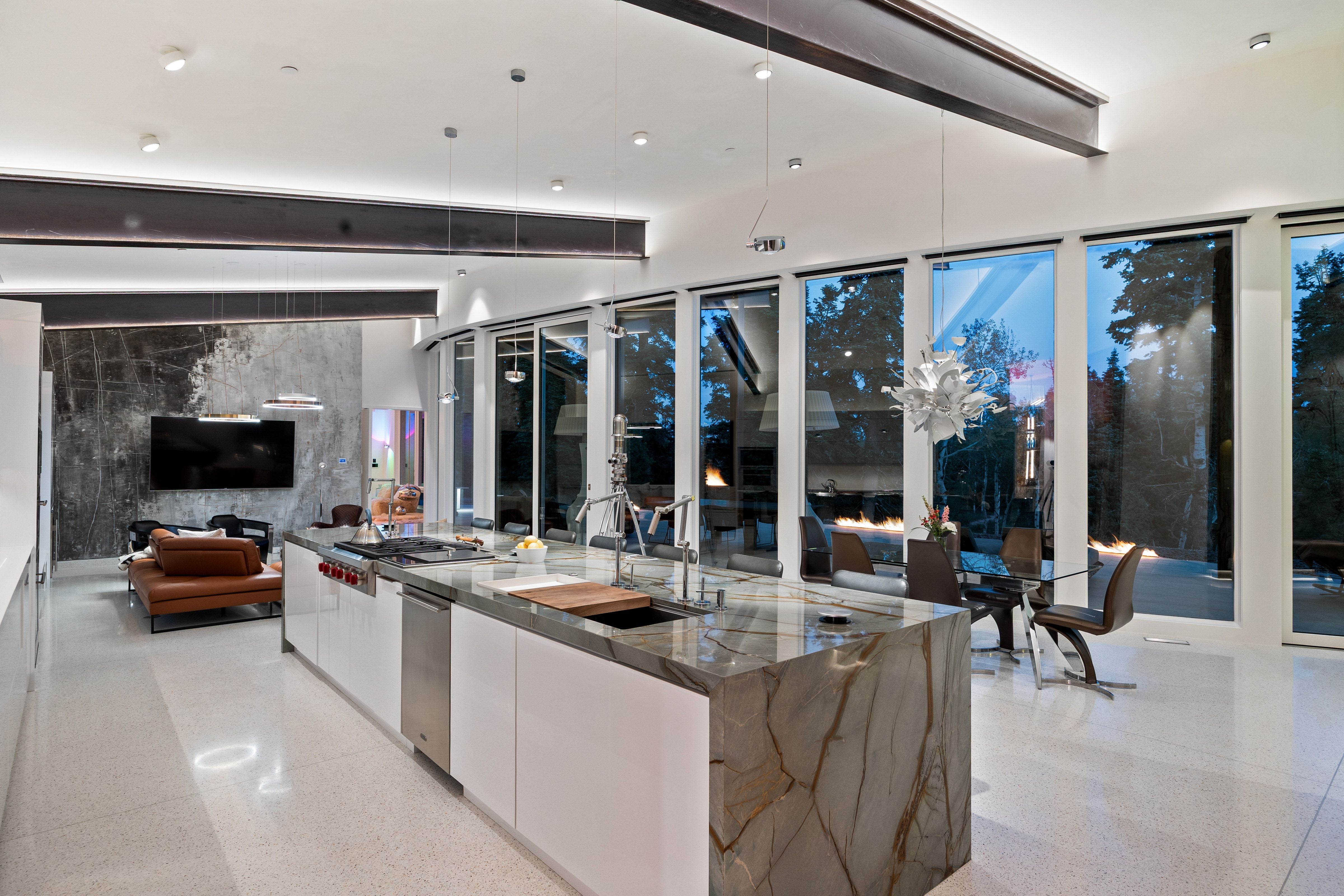 Open-concept living space featuring expansive floor-to-ceiling windows, high ceilings with exposed structural beams, and recessed lighting