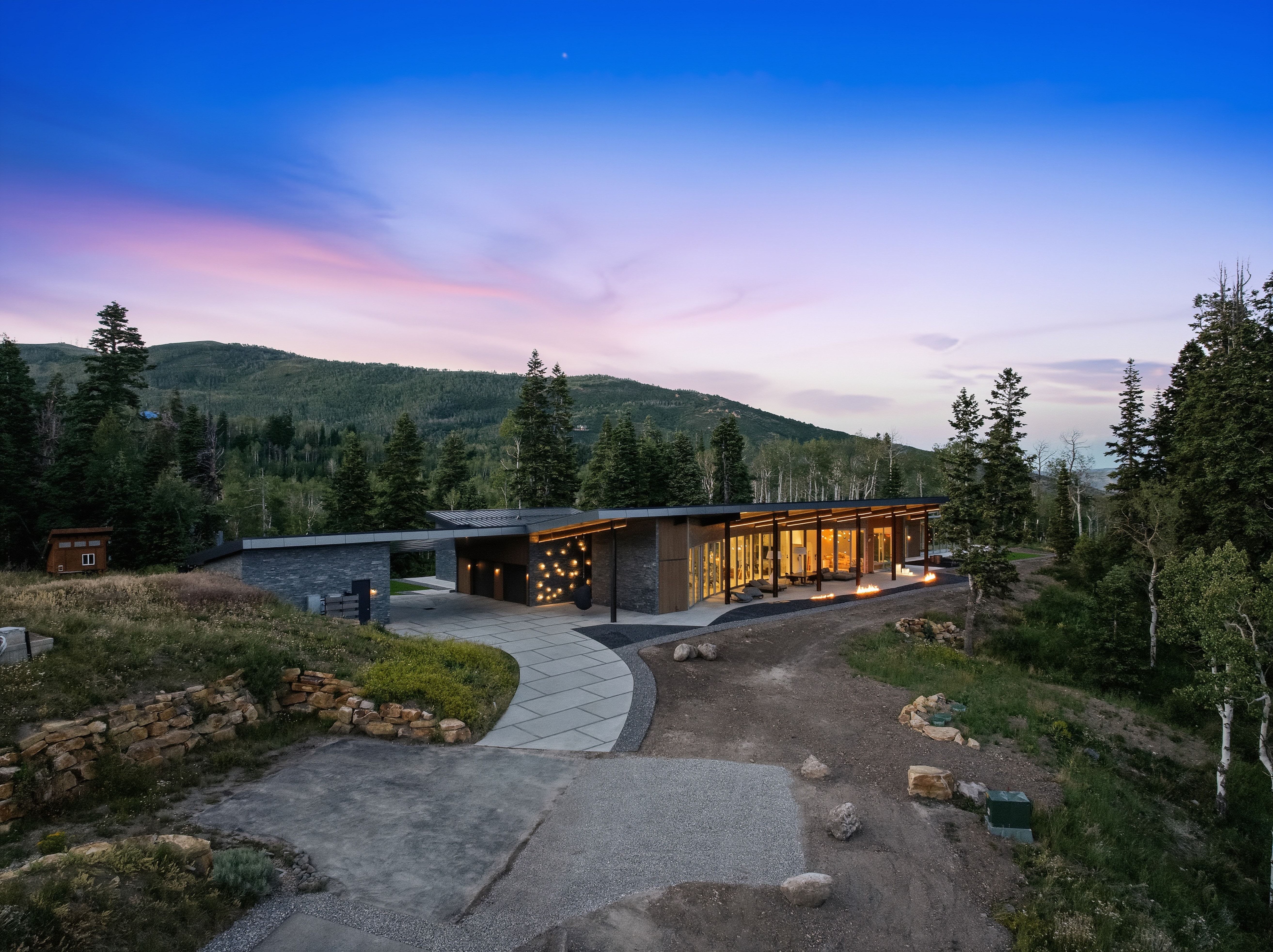 Modern architectural residence featuring extensive glass paneling, stone accents, and a distinctive flat roofline