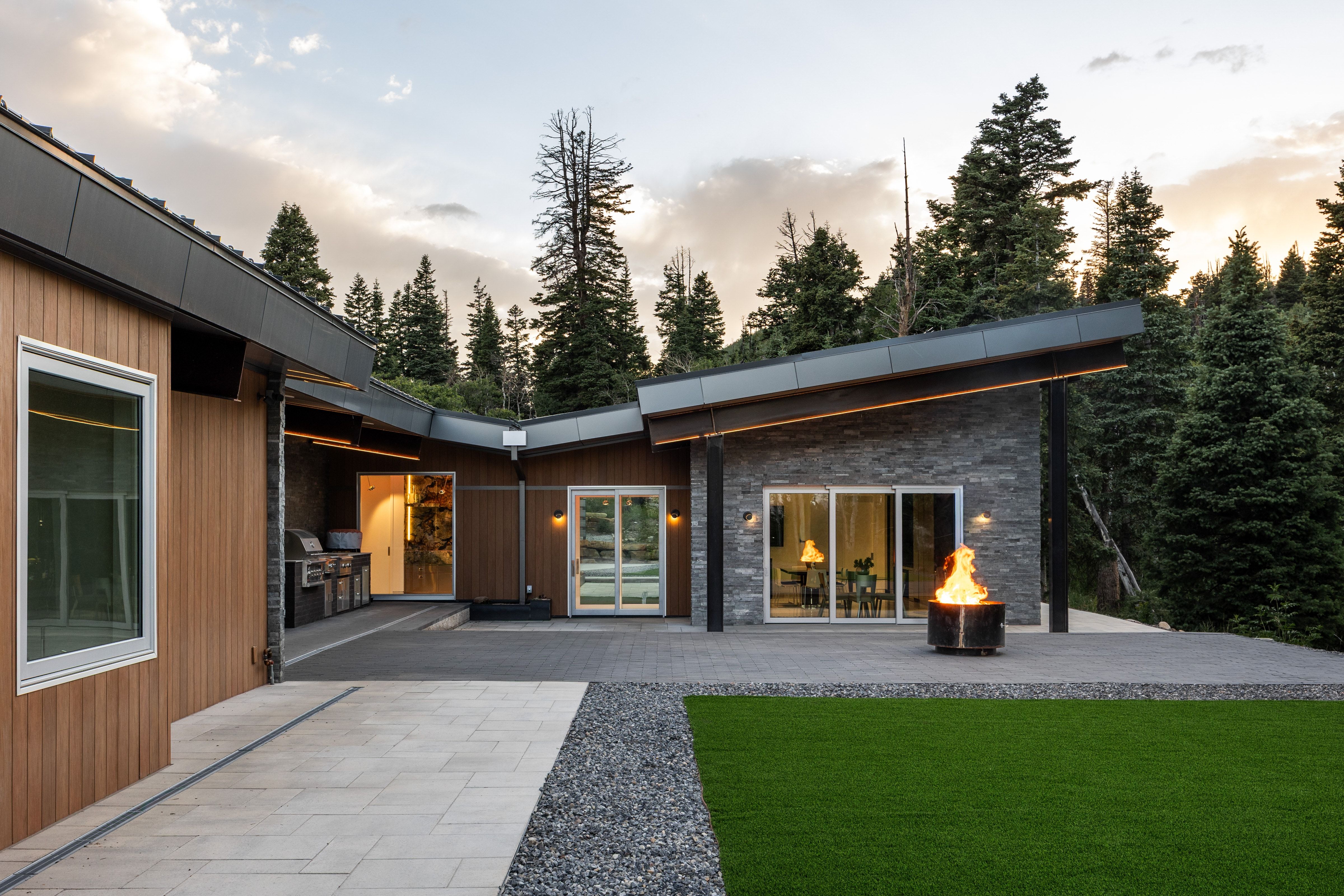 Modern exterior featuring horizontal wood-finish siding, a dark stone accent wall, and a black metal-clad roofline