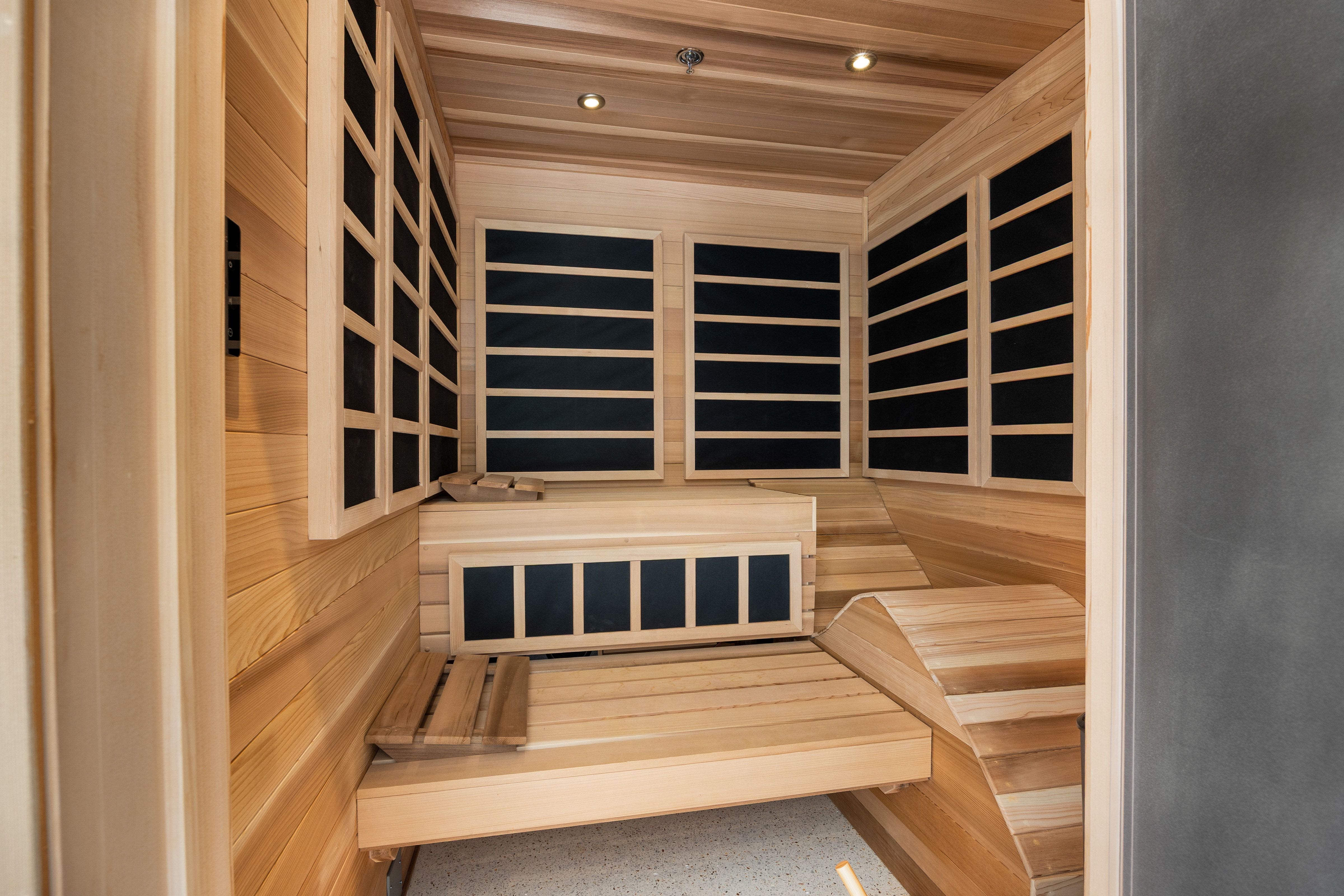 Built-in sauna featuring wood-paneled walls and ceiling, recessed lighting, integrated bench seating, and multiple heating panels
