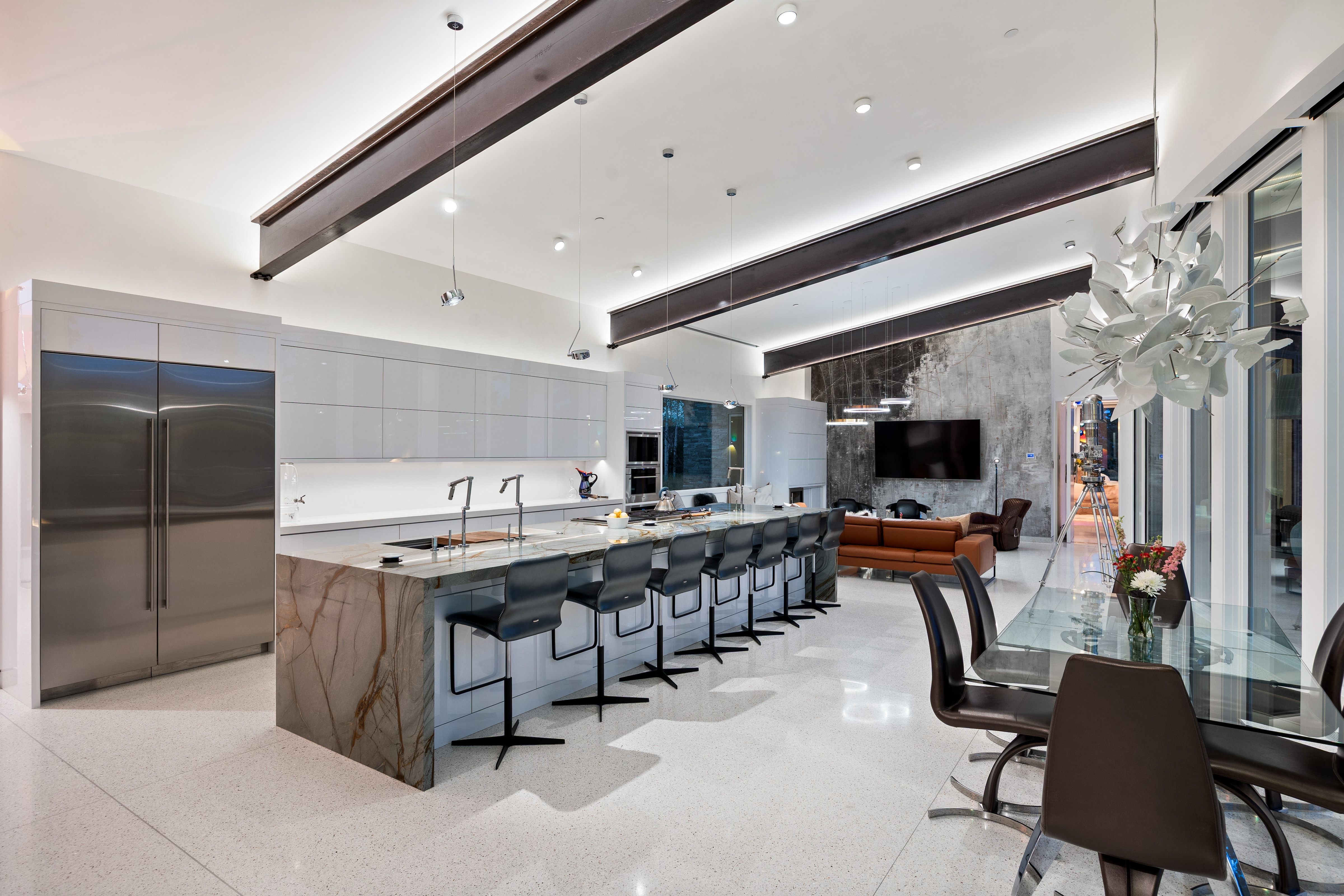 Open-concept kitchen featuring an expansive island with waterfall countertop, integrated cooktop, and seating for multiple guests