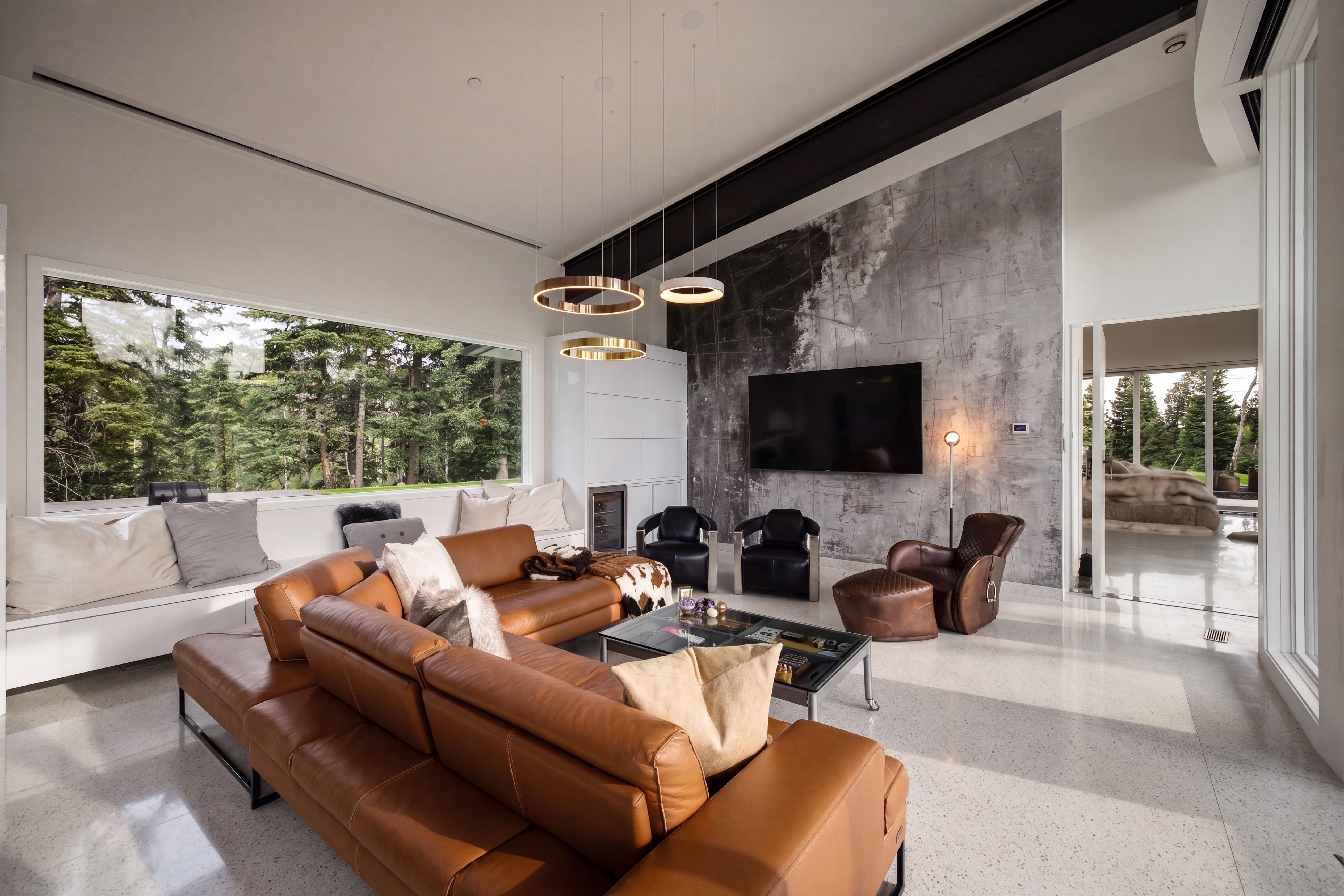 Contemporary living area featuring a full-width picture window, concrete-finish accent wall, and recessed lighting