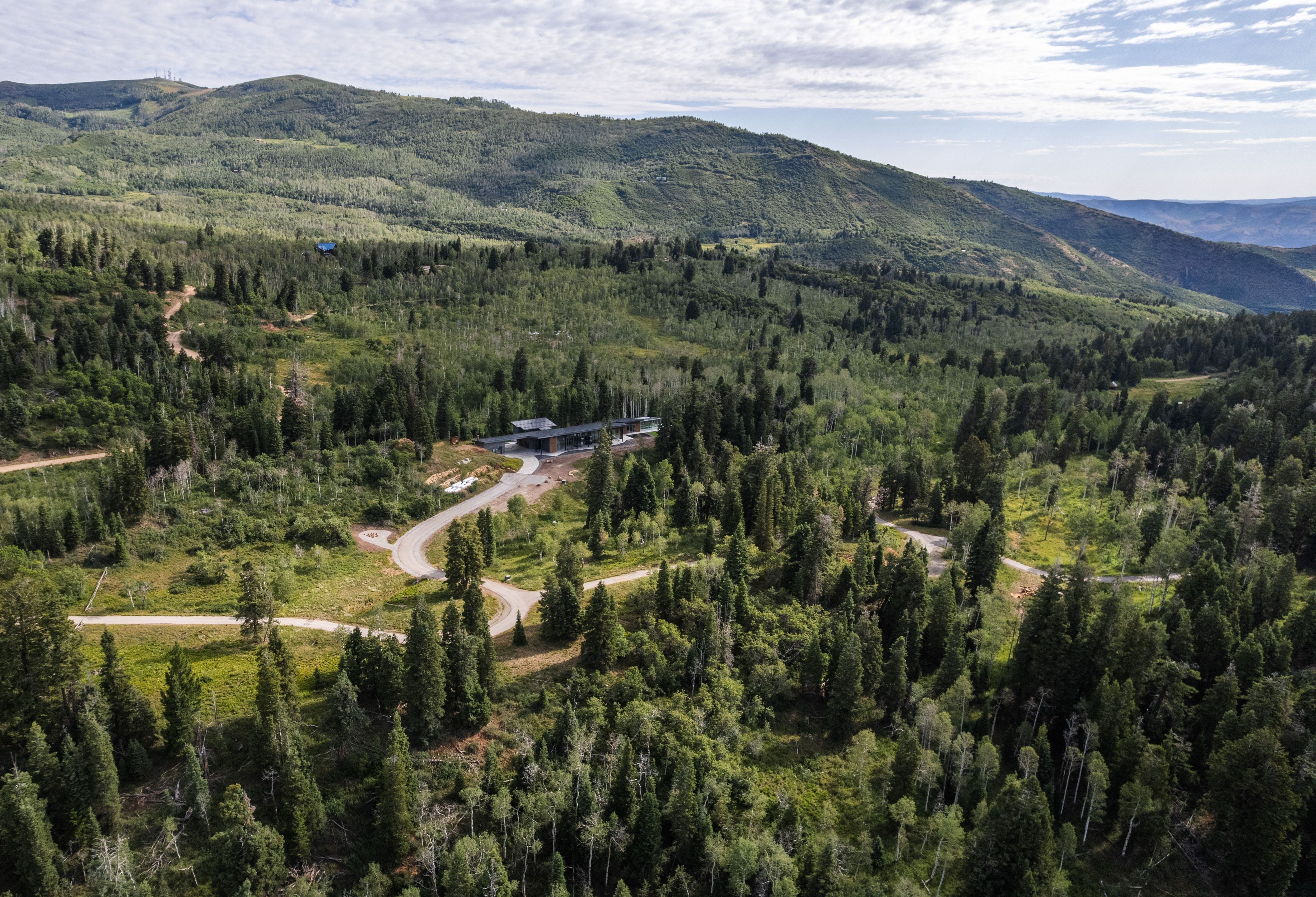 Modern mountain property with a dark-toned exterior set amidst dense evergreen and deciduous trees