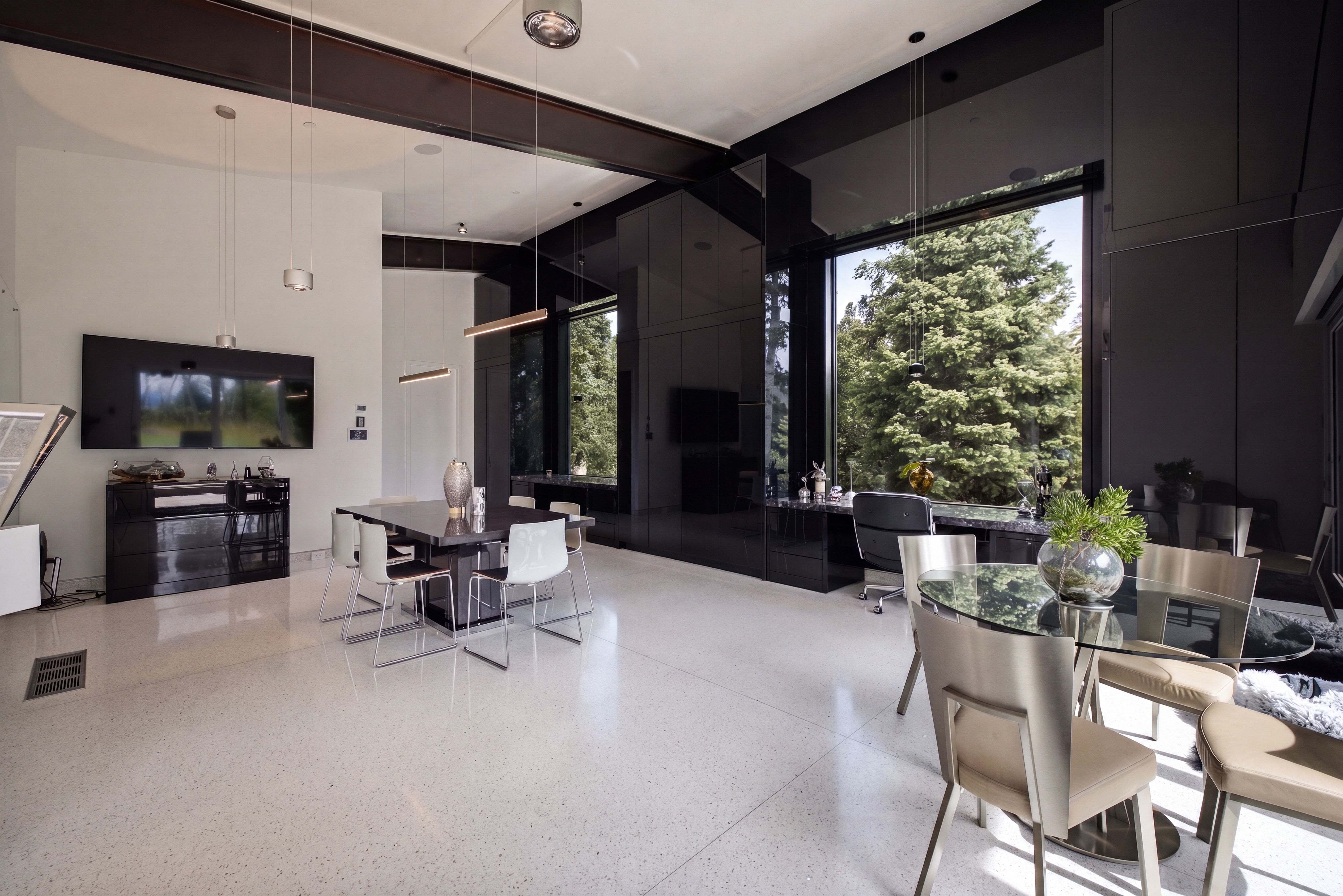Spacious interior featuring a large picture window, high ceilings with exposed beams, light-colored flooring, and built-in dark cabinetry