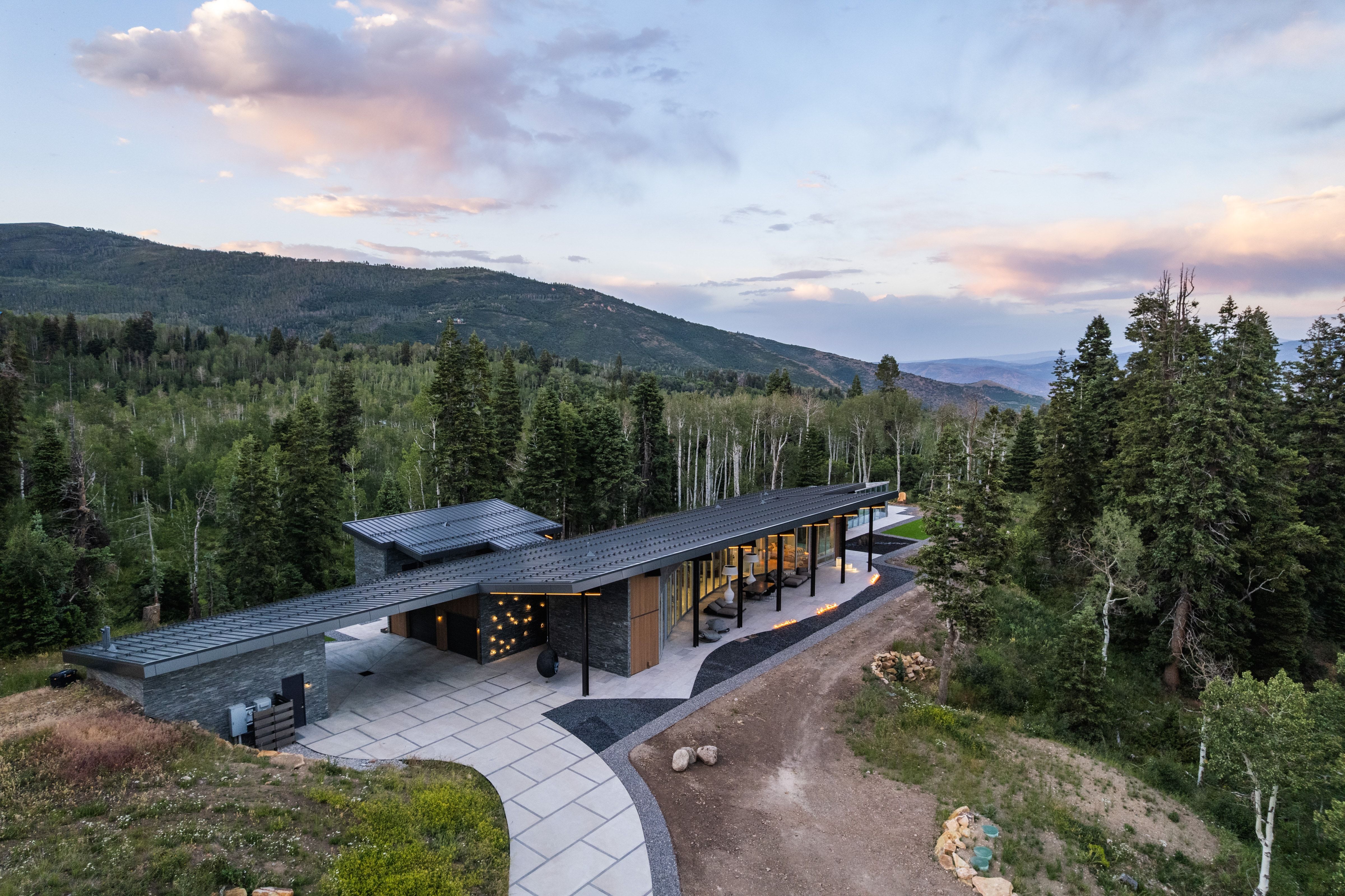 Contemporary mountain residence featuring a prominent flat roofline, extensive exterior stone cladding, and floor-to-ceiling windows