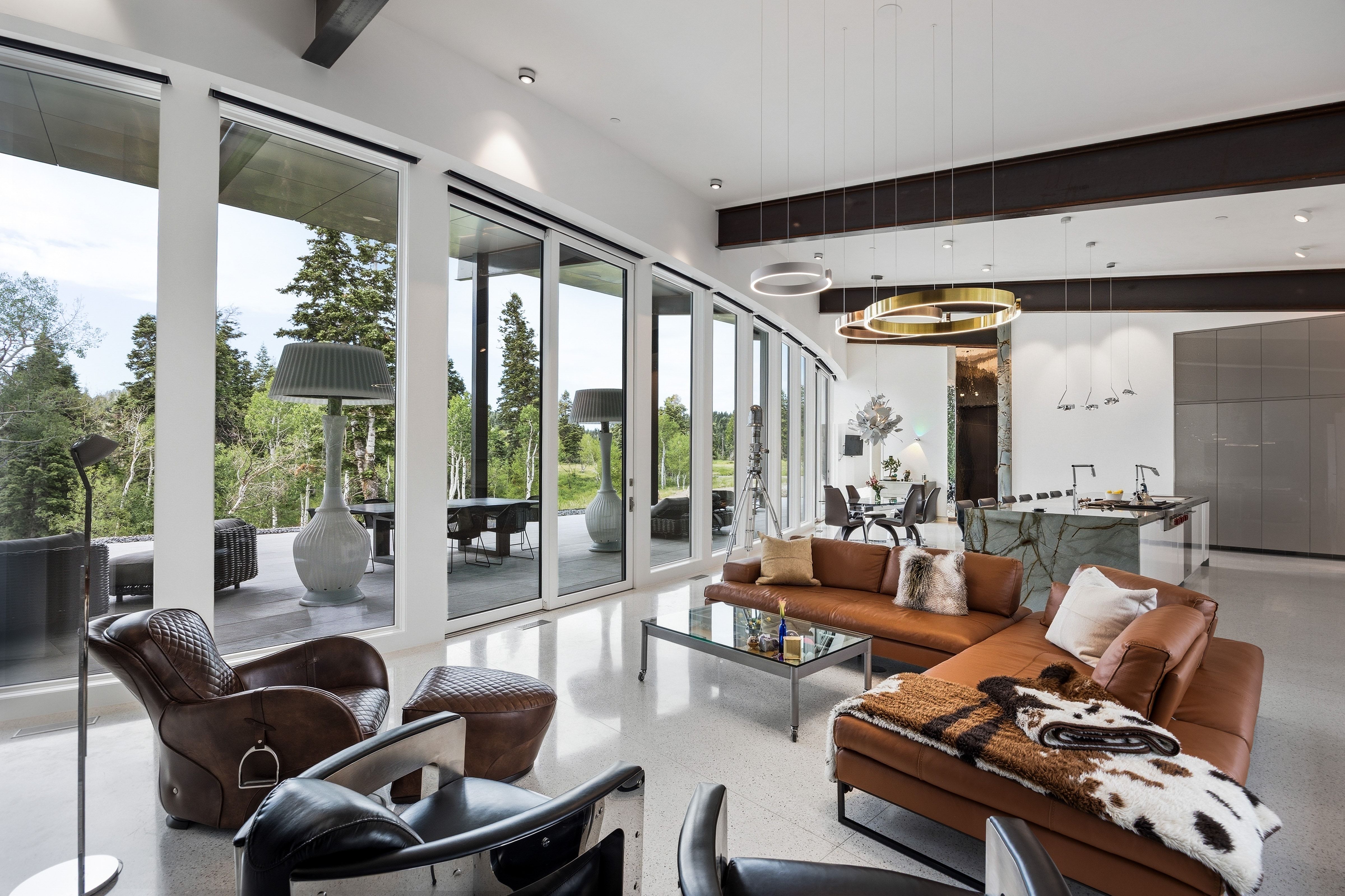 Spacious living area featuring floor-to-ceiling sliding glass doors, polished concrete flooring, exposed ceiling beams, and contemporary pendant lighting