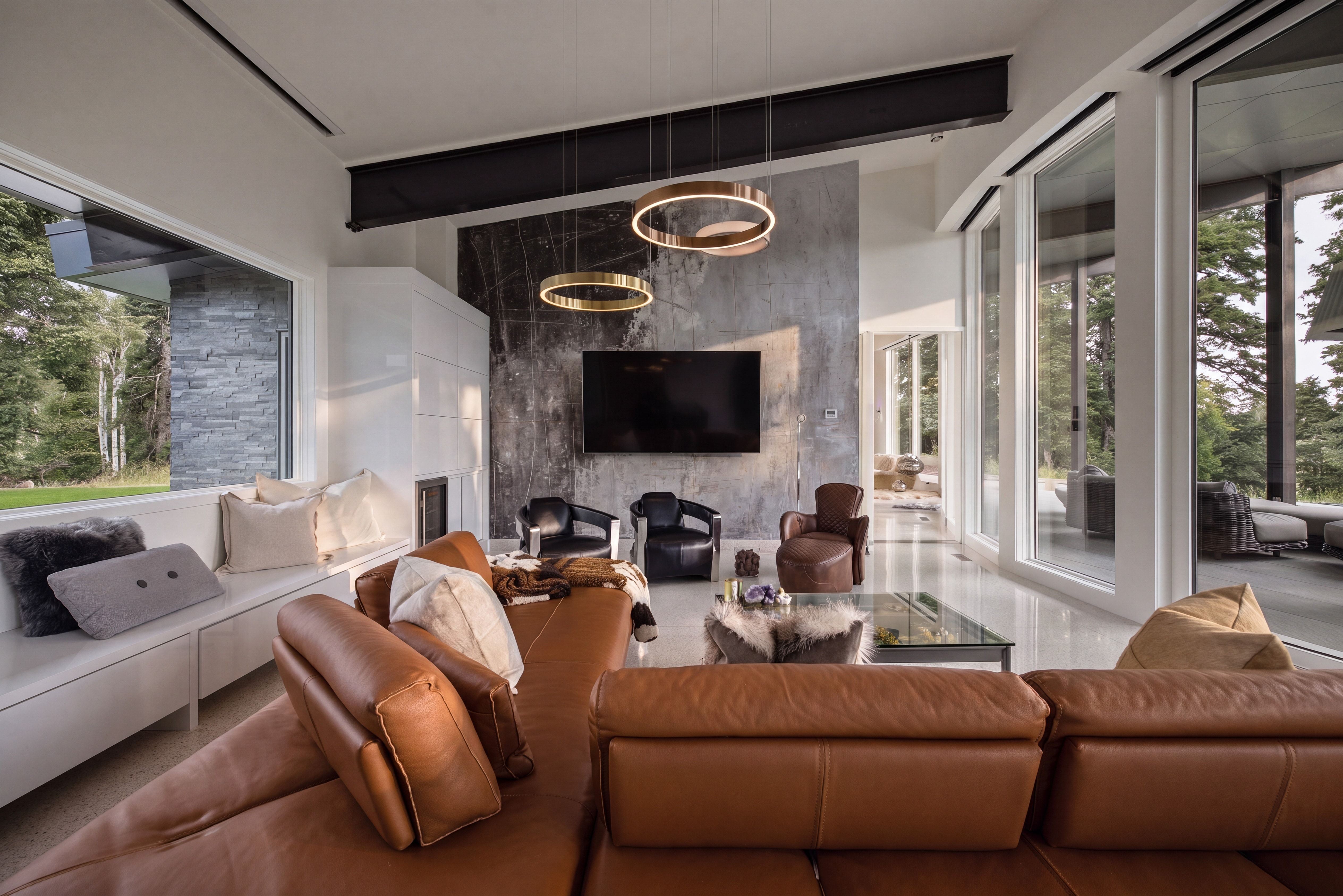 Spacious living area featuring floor-to-ceiling windows, a built-in window bench, a modern fireplace surround, and contemporary circular pendant lighting