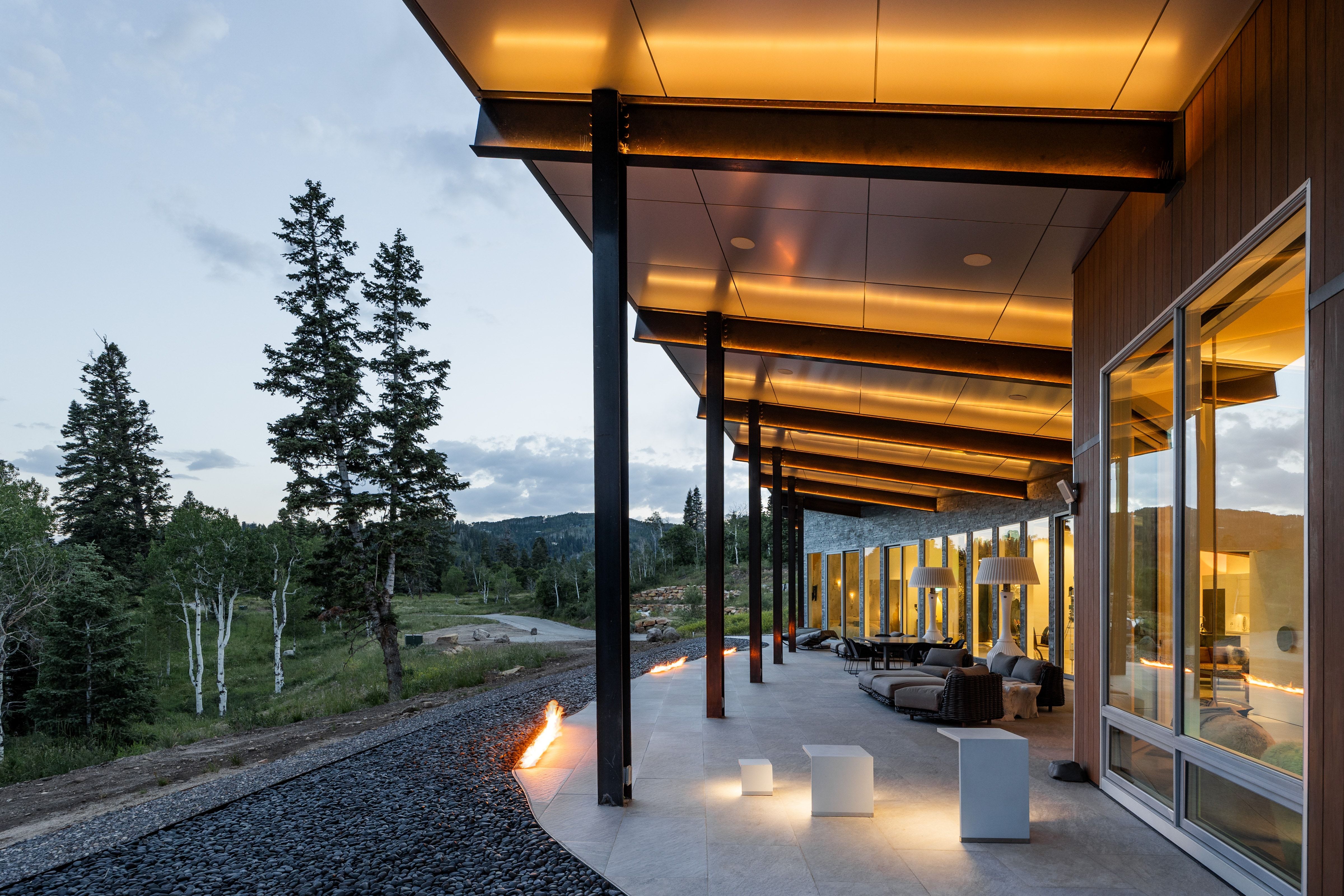 Expansive covered patio featuring a pitched ceiling with integrated lighting, exposed structural beams, and recessed lighting