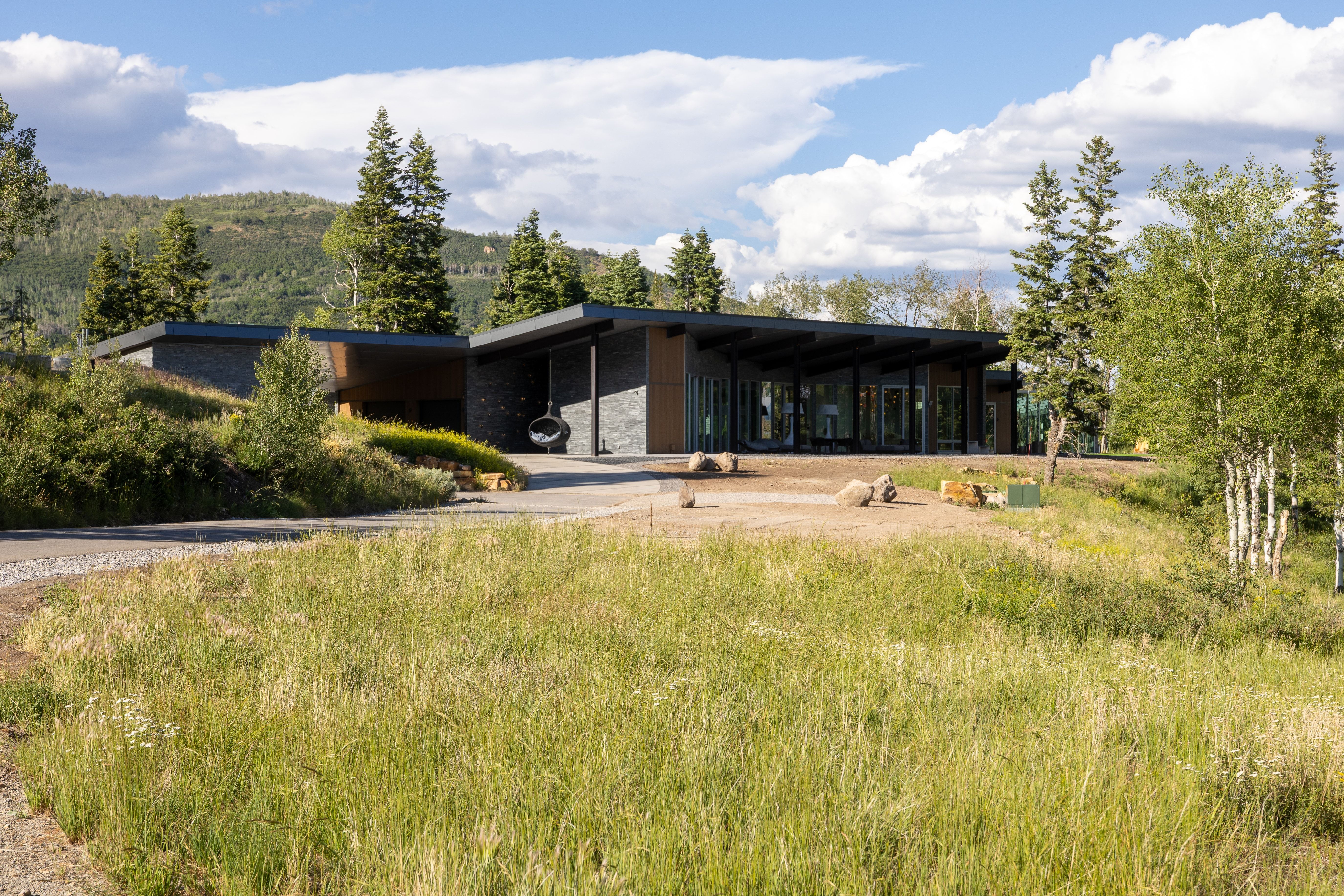 Contemporary multi-level residence featuring a flat roofline, stone veneer accents, and extensive floor-to-ceiling window walls