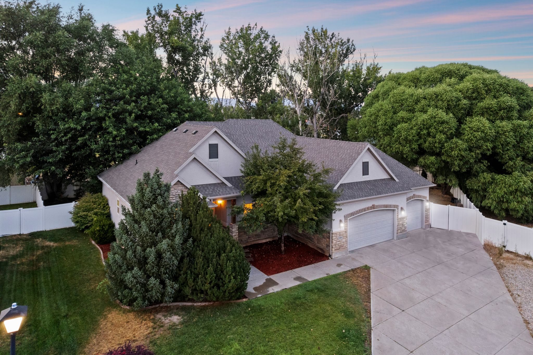 Contemporary residence featuring a two-car garage with arched entries, stone accents, and exterior wall sconces