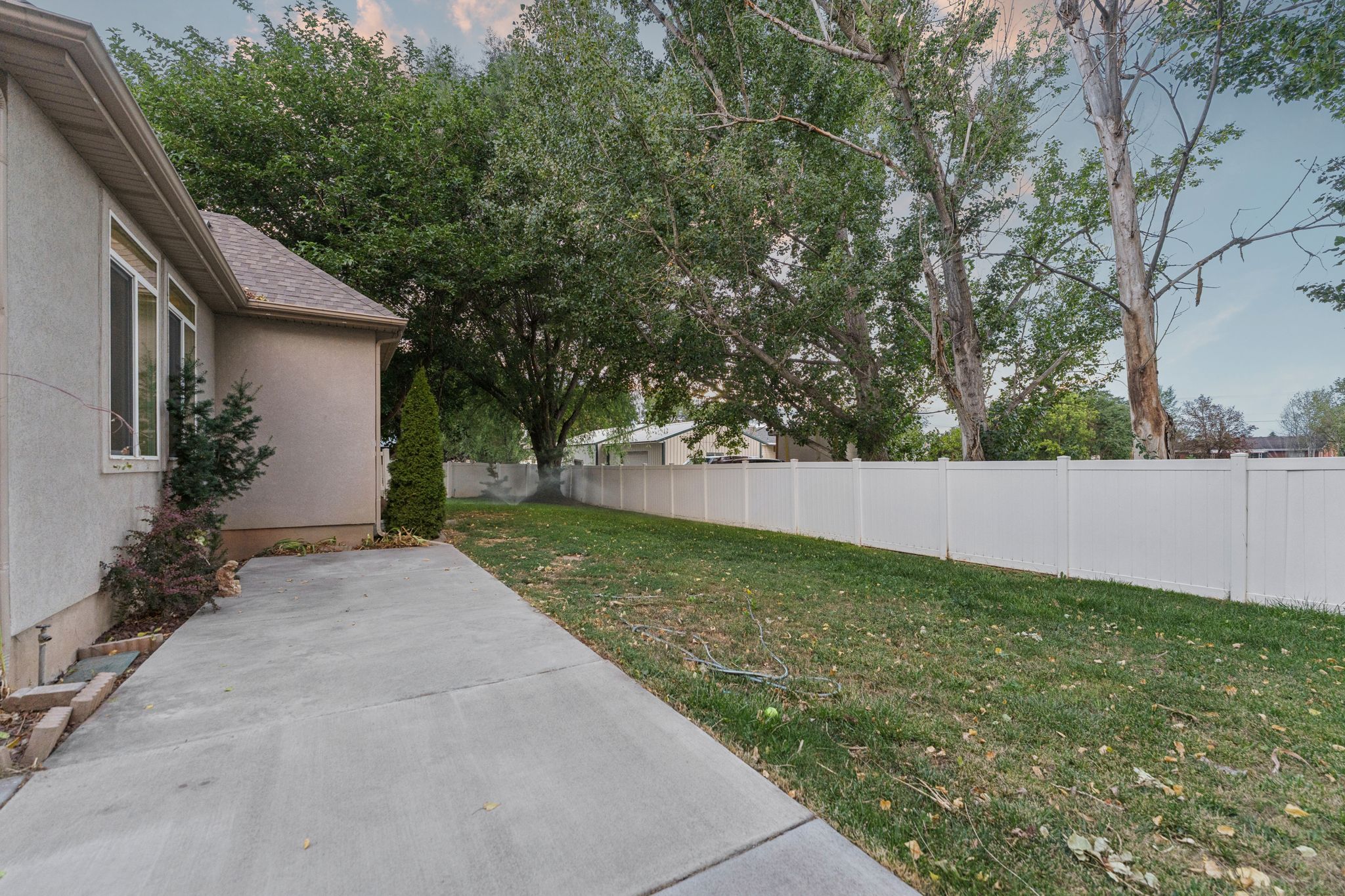 Expansive lawn area bordered by a white privacy fence and mature trees
