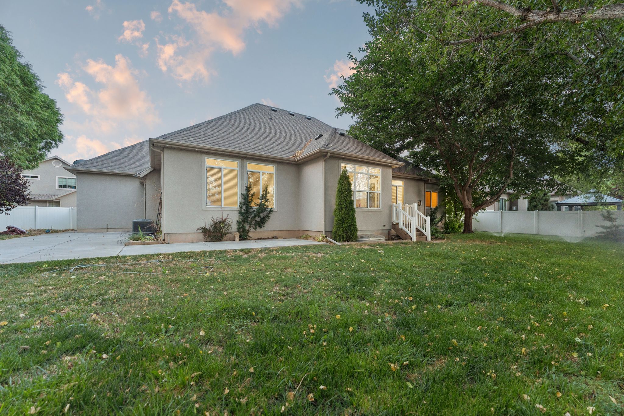 Spacious backyard with mature tree, fenced perimeter, and a concrete patio