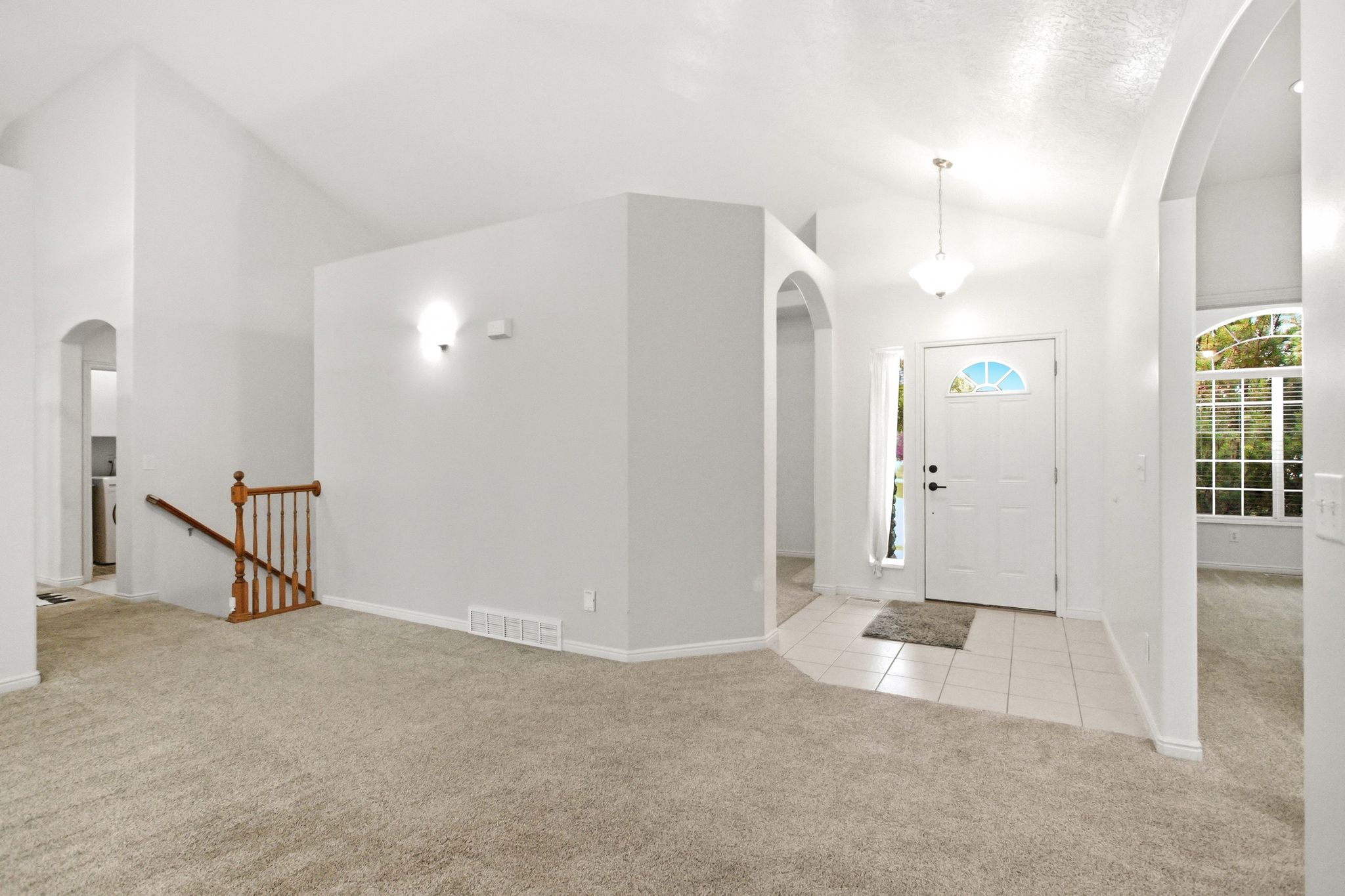 Entryway featuring a white paneled door with an arched window, tiled flooring, and a pendant light fixture